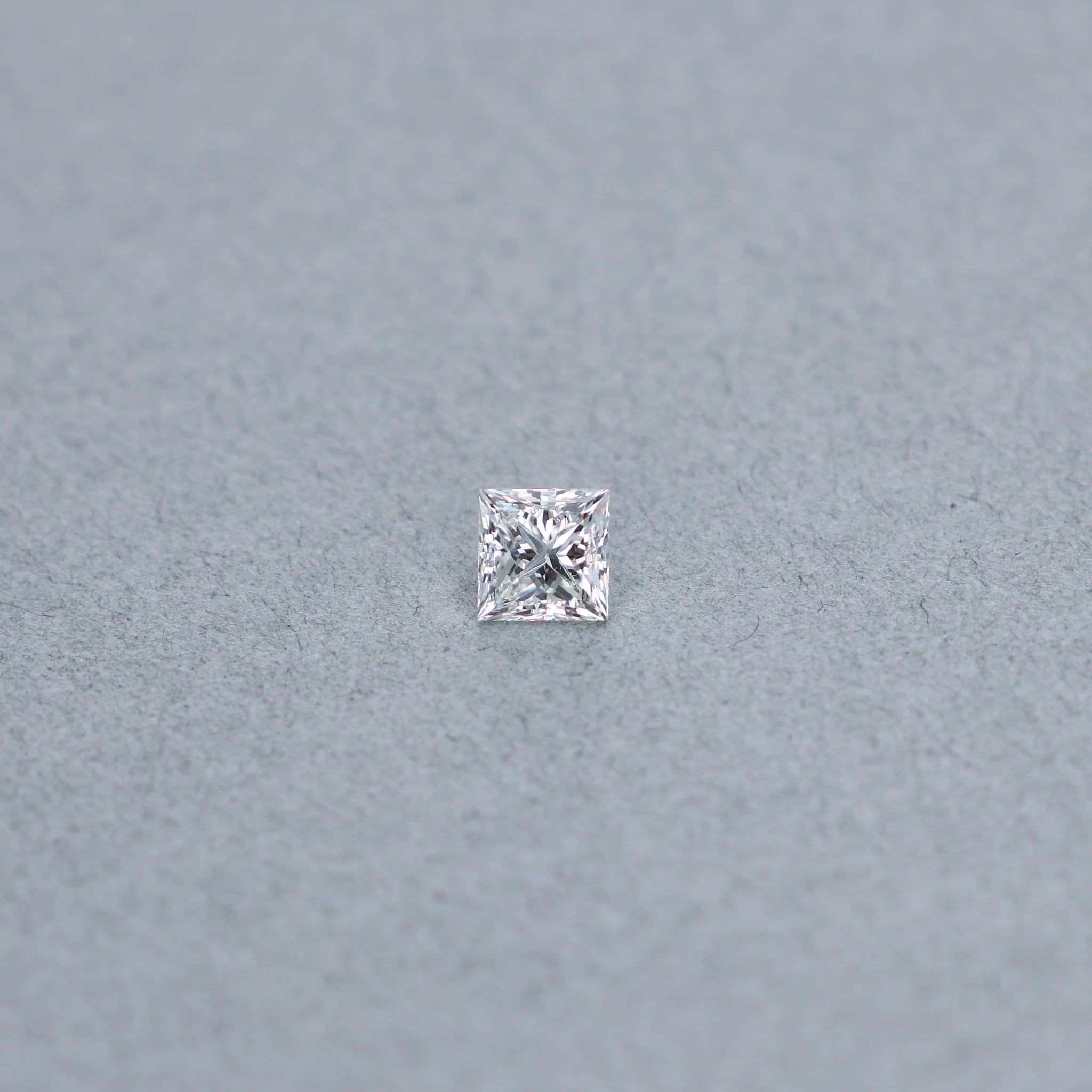 Princess cut 0.99 carat diamond graded GVS2 on a grey background