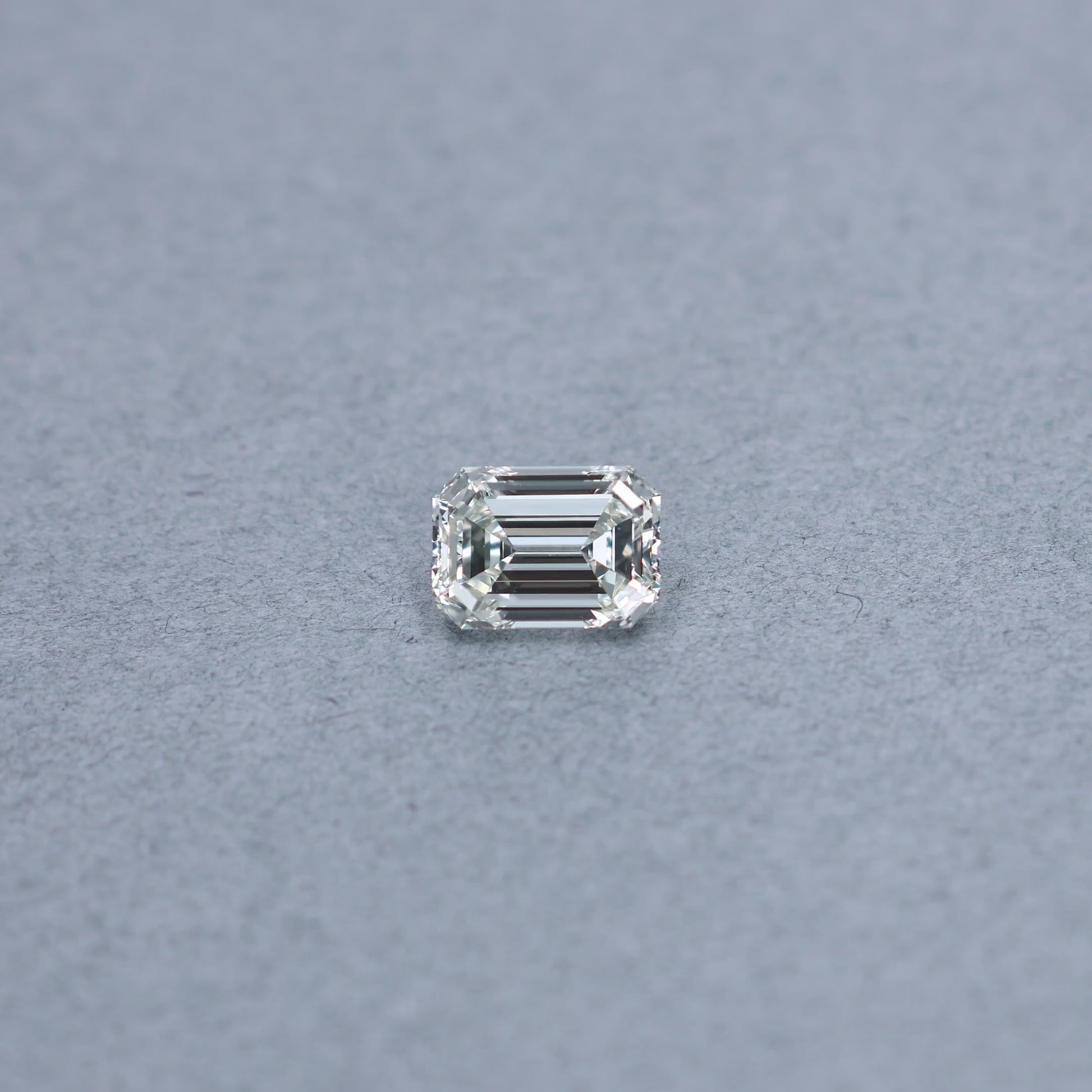 Emerald cut 2.51 carat GIA certified diamond graded JVS1 on a grey background