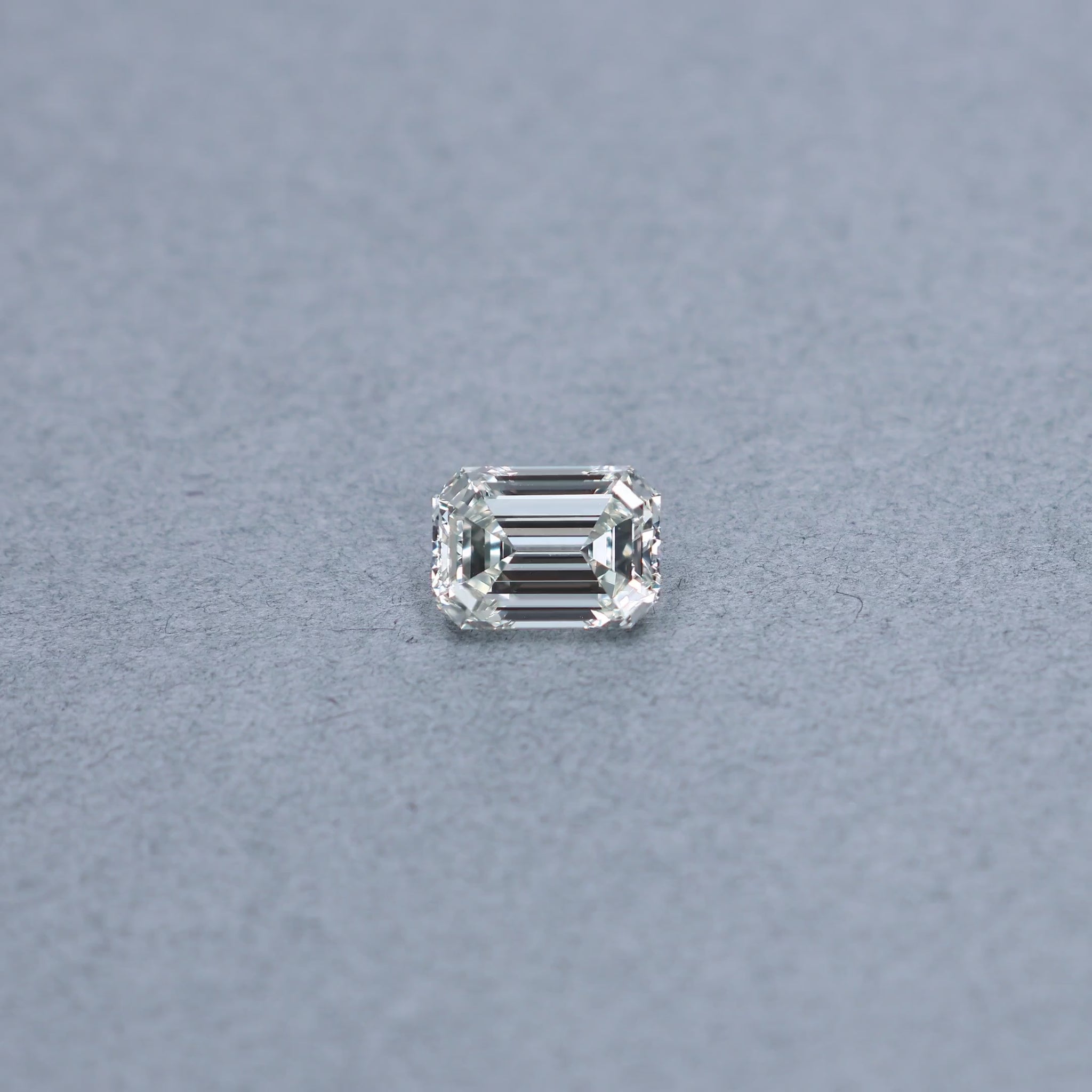 Emerald cut 2.51 carat GIA certified diamond graded JVS1 on a grey background