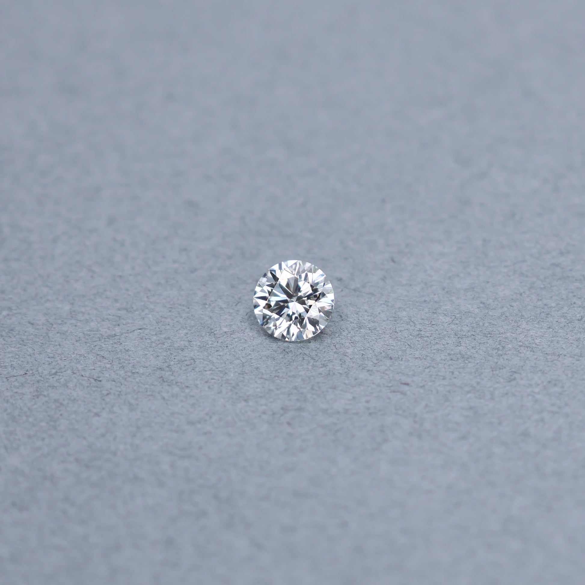 Round 0.90 carat GIA certified diamond graded JVS2 on a grey background