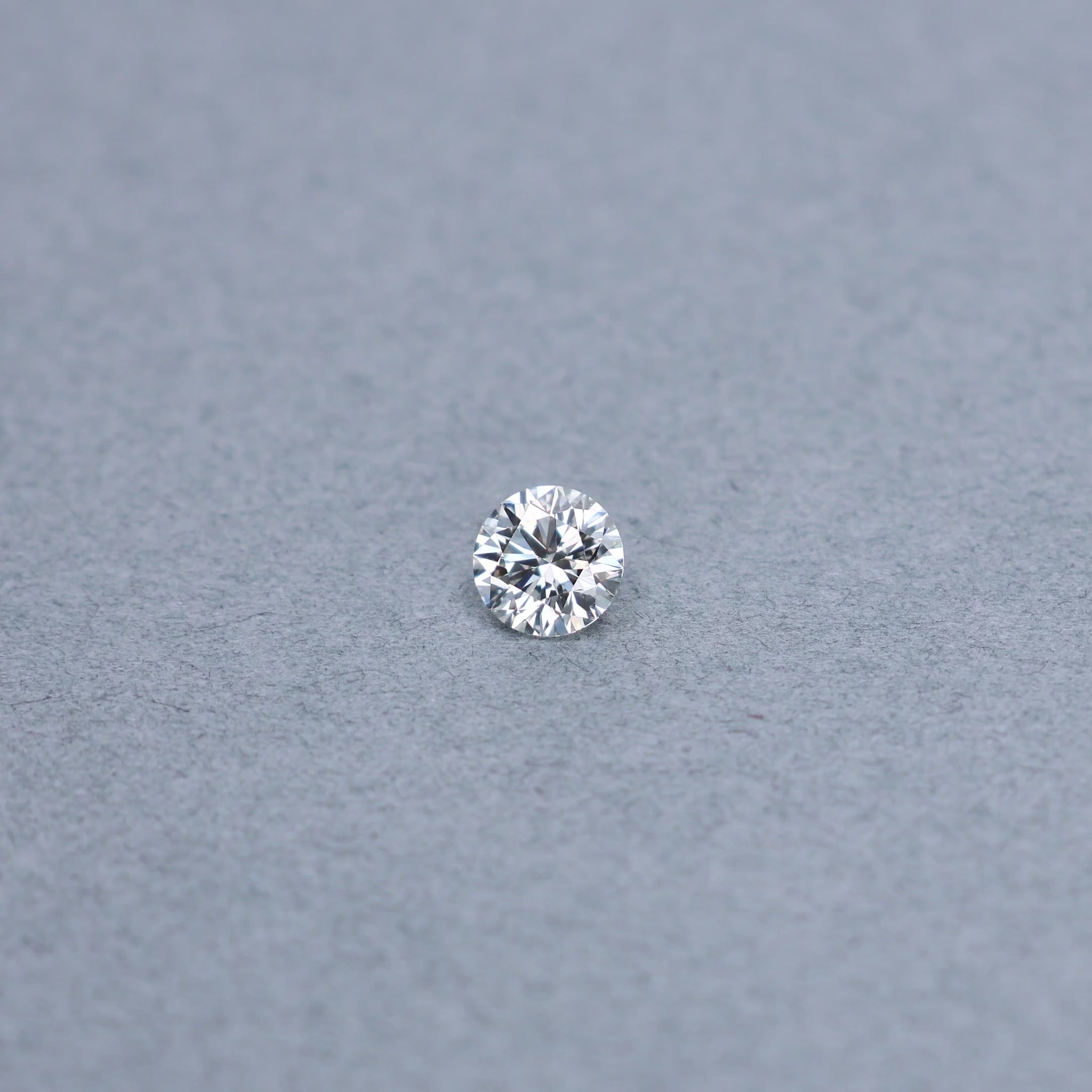Round 0.90 carat GIA certified diamond graded JVS2 on a grey background
