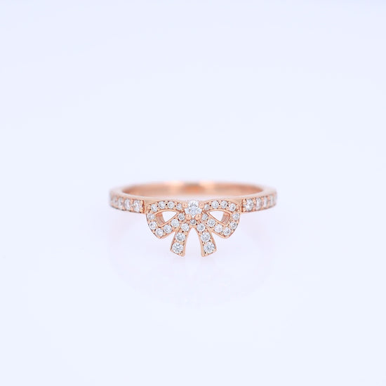 Rose gold pave bow design diamond ring on a white background