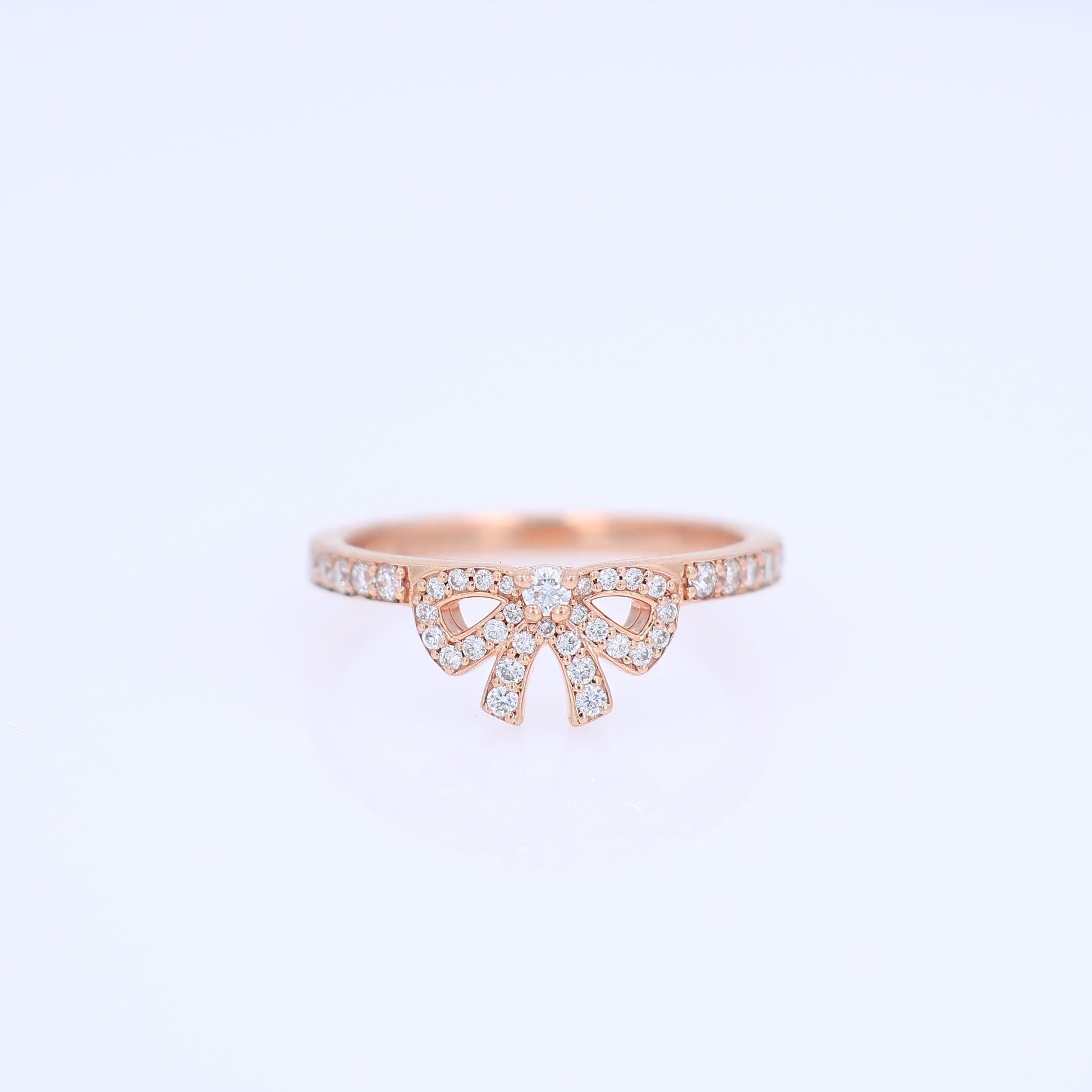 Rose gold pave bow design diamond ring on a white background
