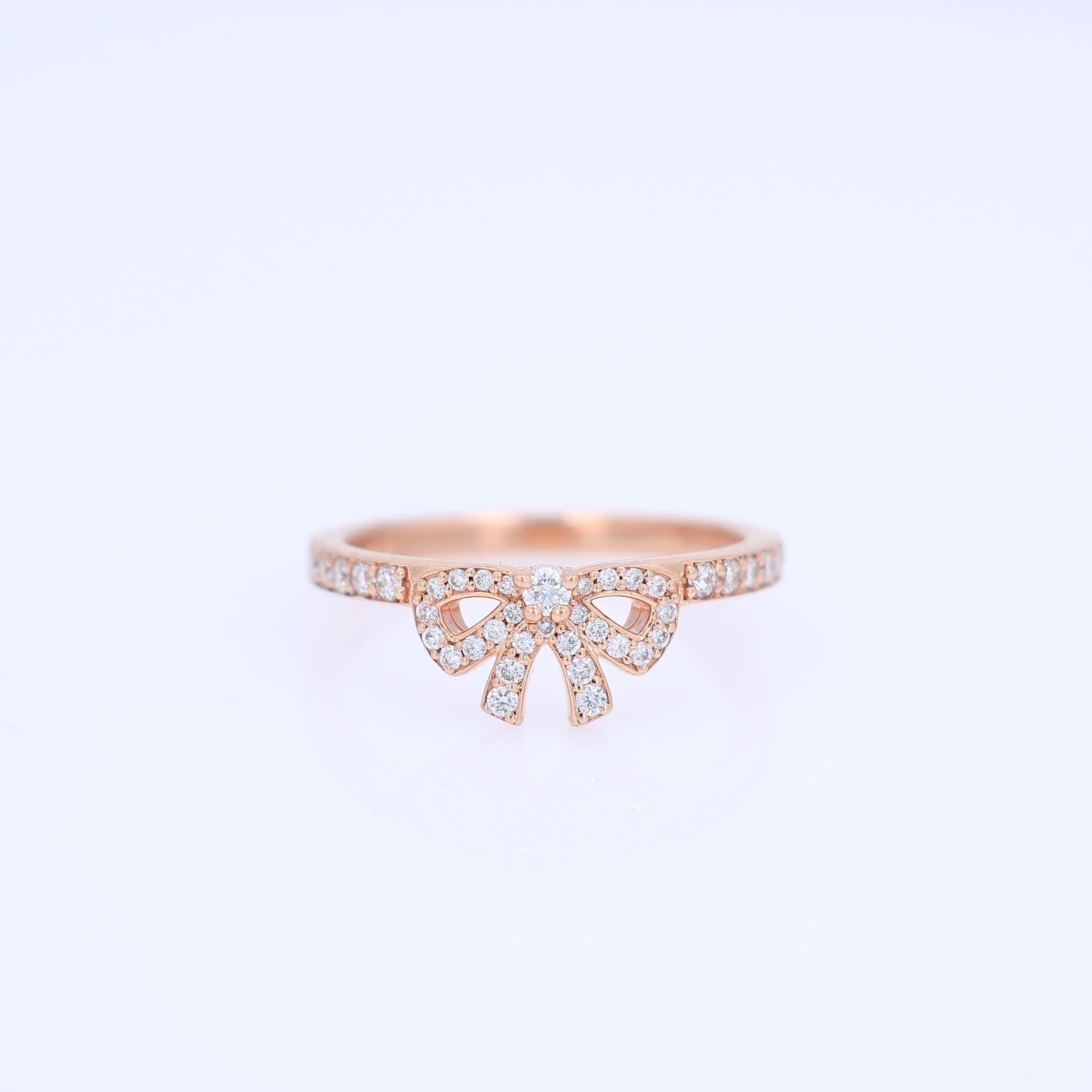 Rose gold pave bow design diamond ring on a white background