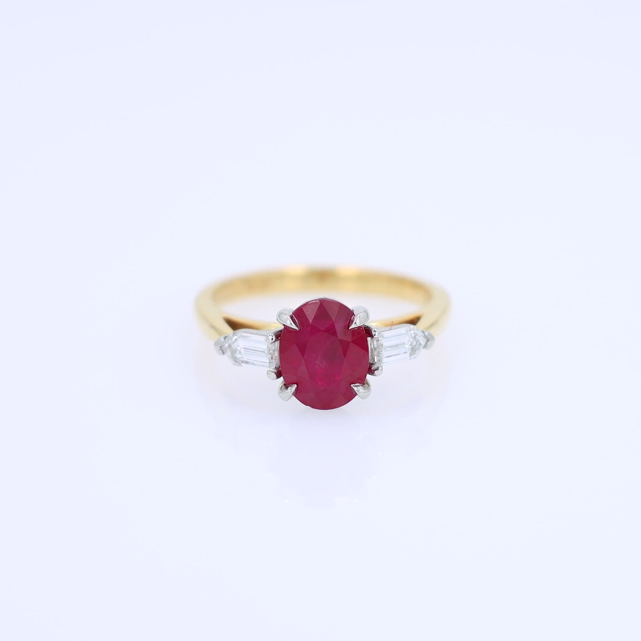 Gold ring with a ruby center and diamond sides on a white background