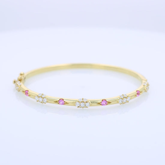 Yellow gold bracelet with pink sapphire and diamond accents on a white background