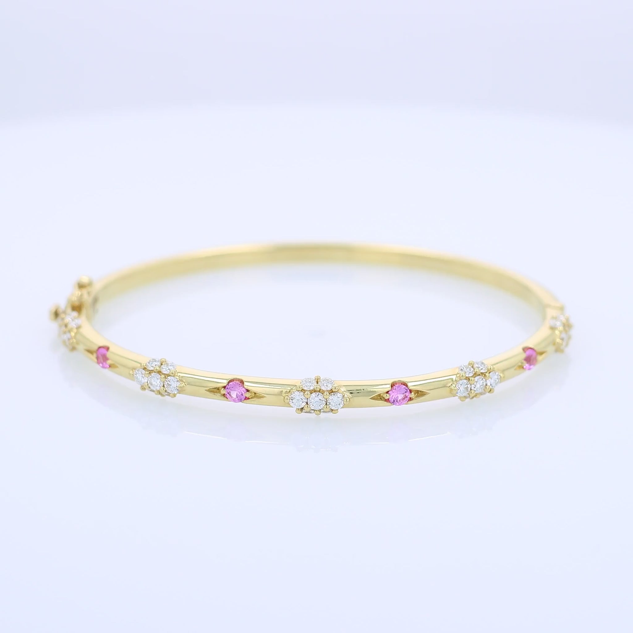Yellow gold bracelet with pink sapphire and diamond accents on a white background