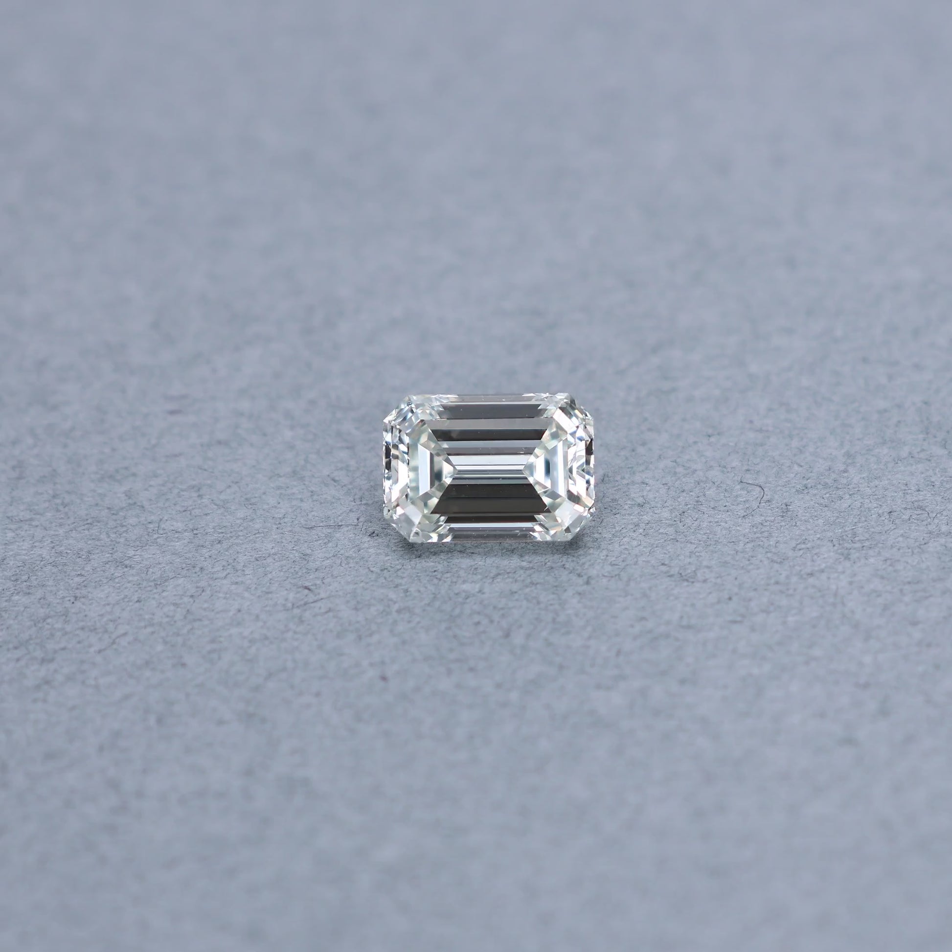 Emerald cut 3.00 carat GIA certified diamond graded JSI1 on a grey background