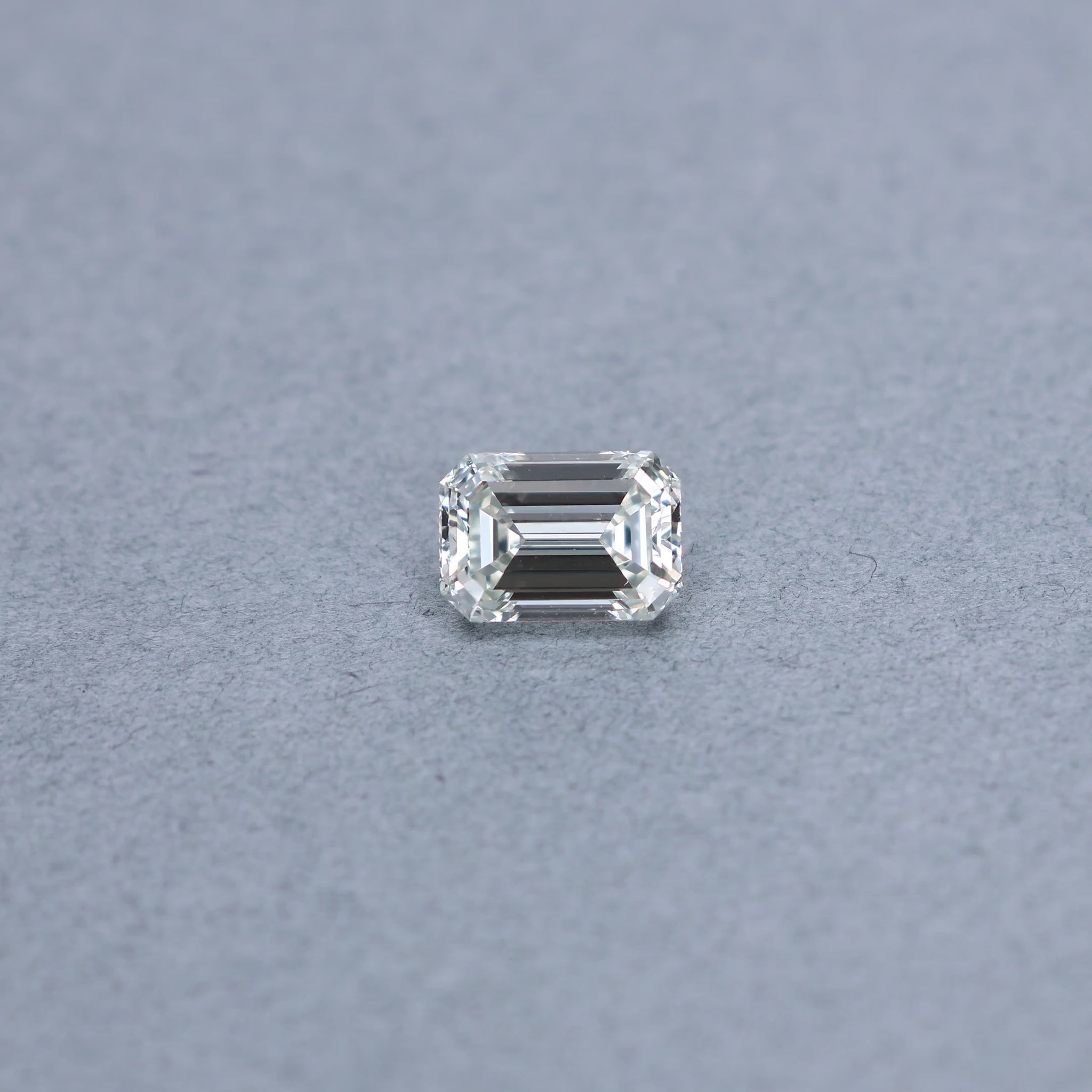 Emerald cut 3.00 carat GIA certified diamond graded JSI1 on a grey background