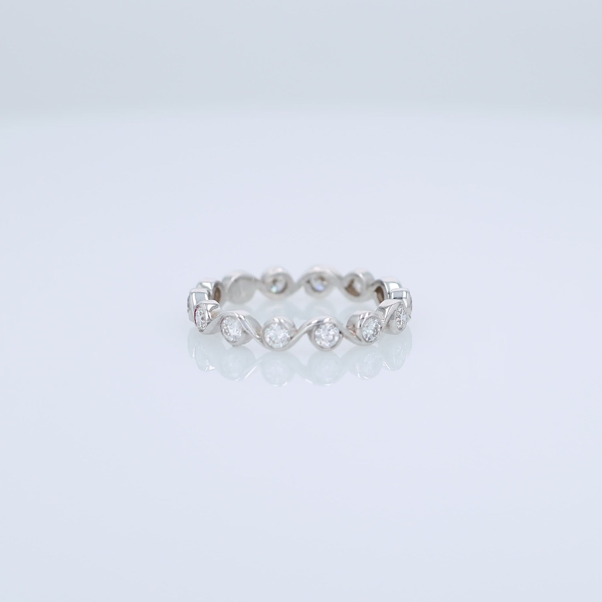 White gold ring with bezel set diamonds on a white background