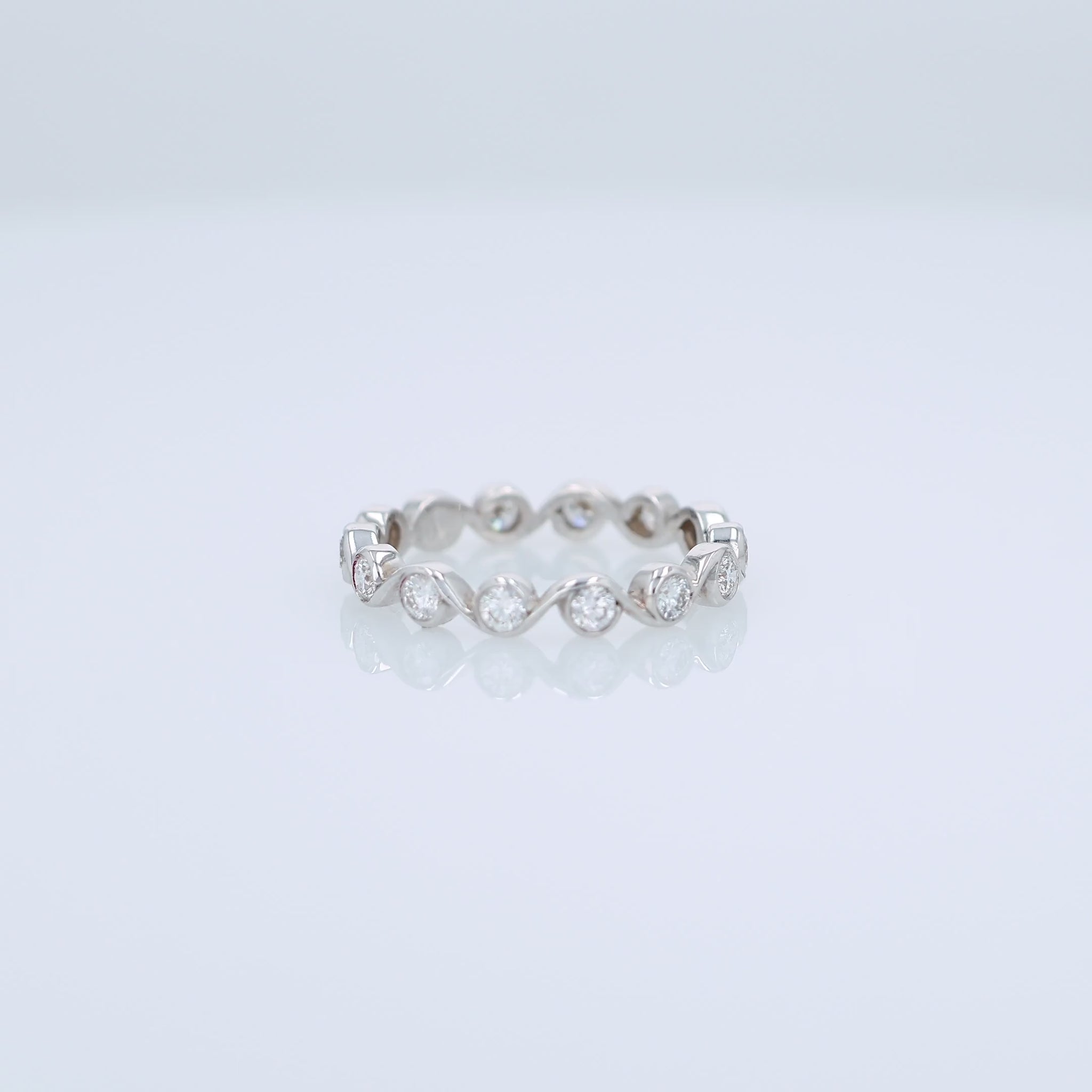 White gold ring with bezel set diamonds on a white background