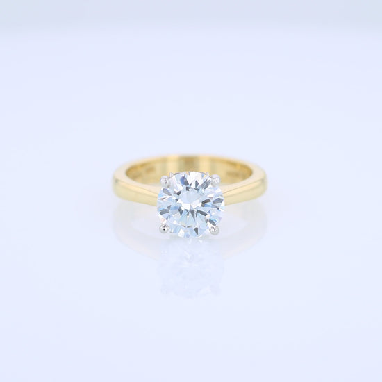 Yellow gold and platinum diamond solitaire engagement ring with diamond accents and a round cubic zirconia center on a white background