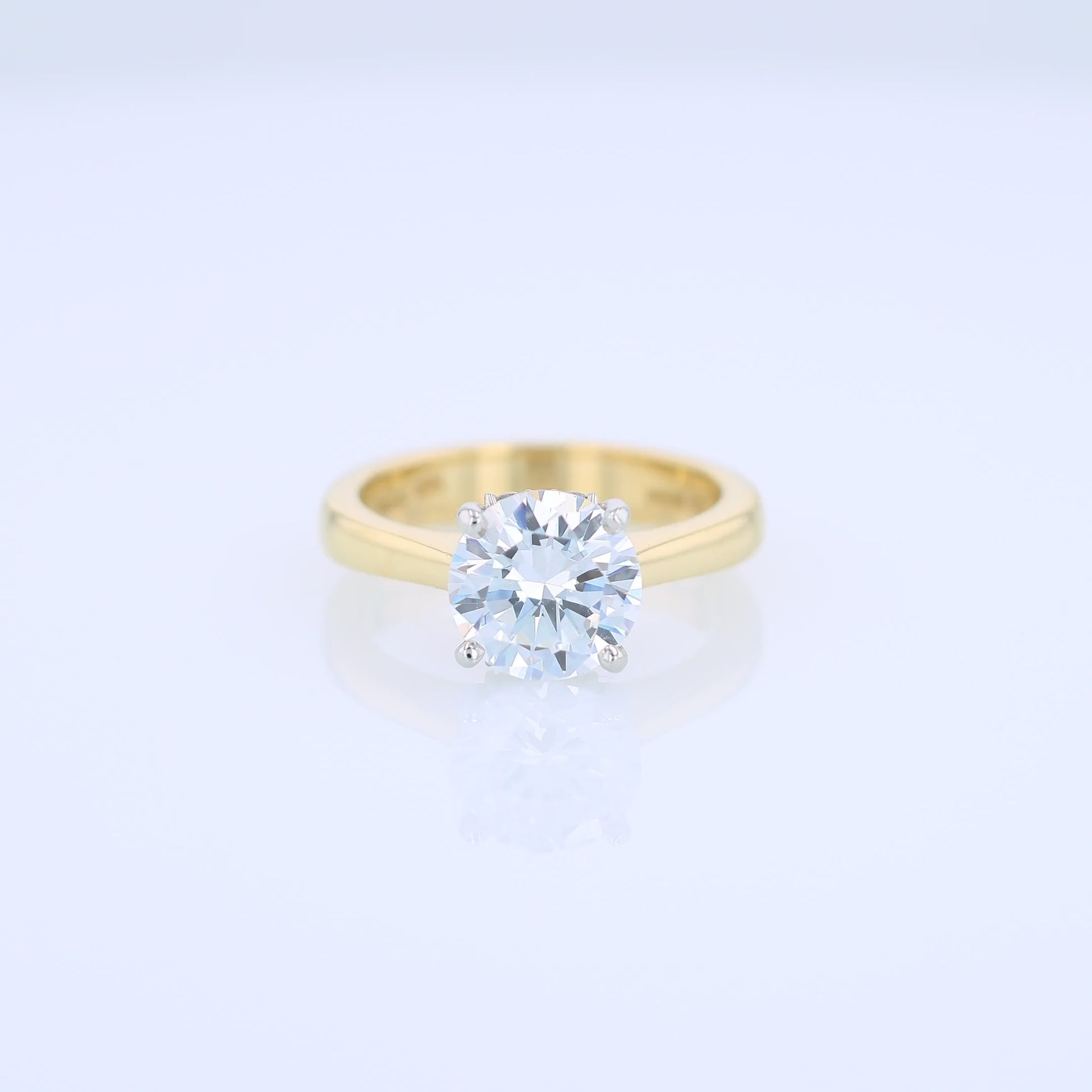 Yellow gold and platinum diamond solitaire engagement ring with diamond accents and a round cubic zirconia center on a white background
