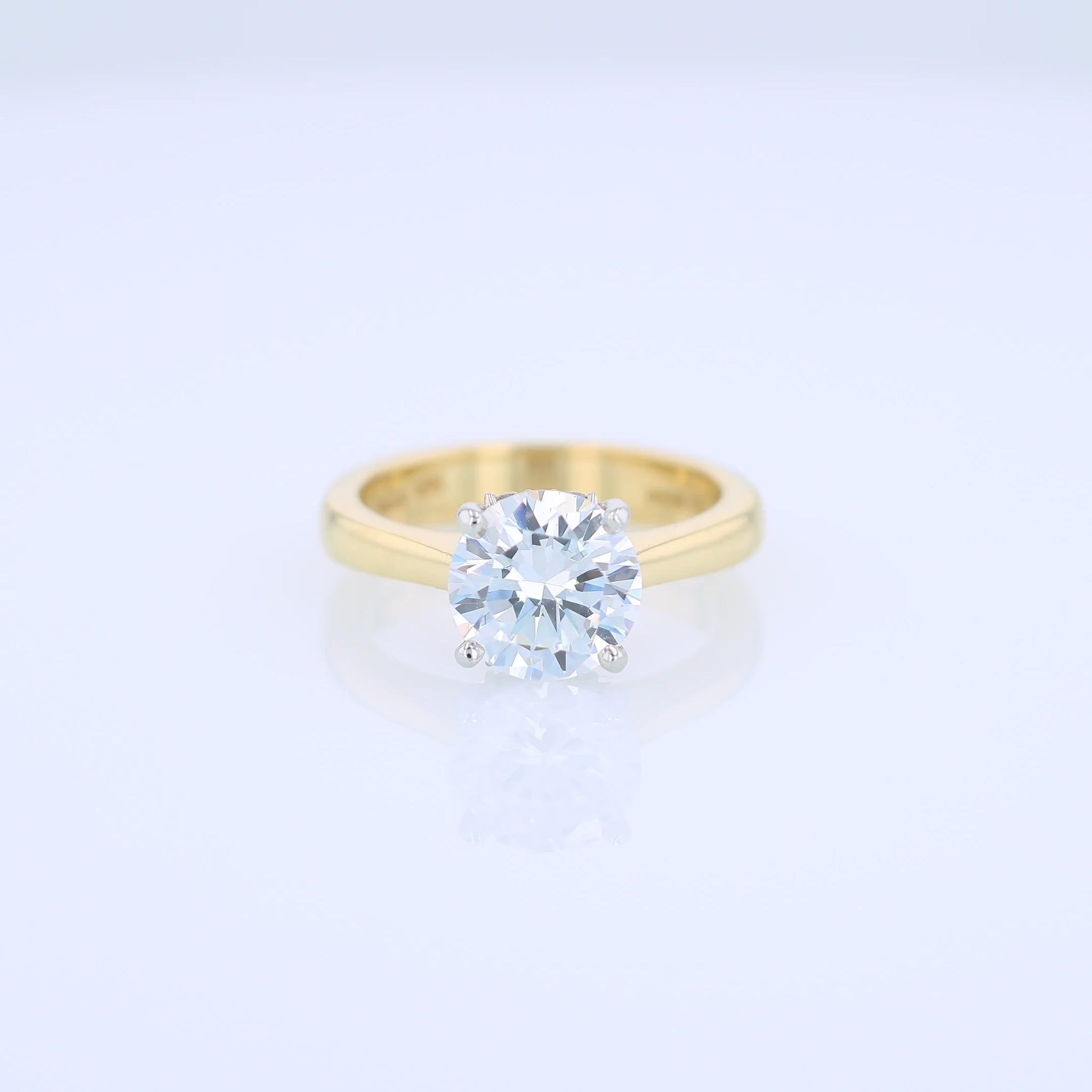 Yellow gold and platinum diamond solitaire engagement ring with diamond accents and a round cubic zirconia center on a white background