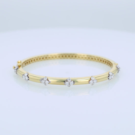 Gold bracelet with diamond cluster accents on a white background
