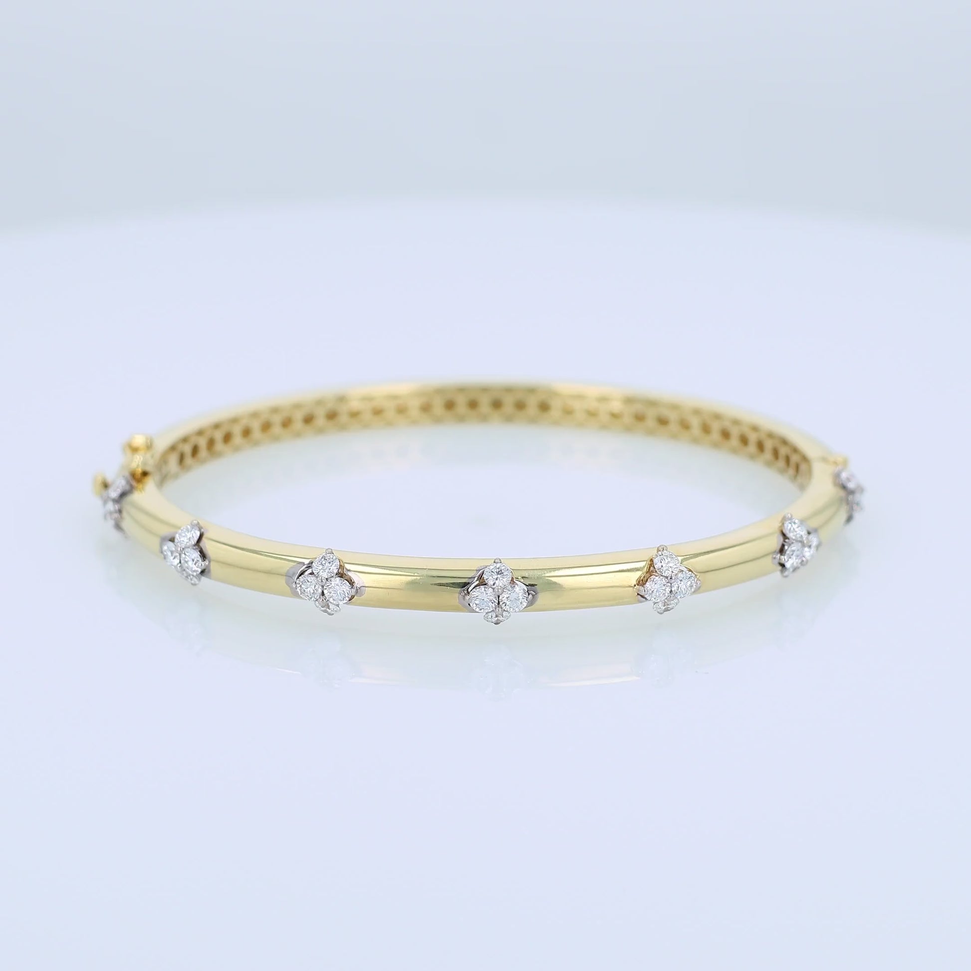 Gold bracelet with diamond cluster accents on a white background