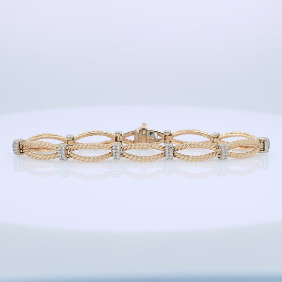 Gold bracelet with interlocking rope design links and alternating white gold diamond station accents on a white background
