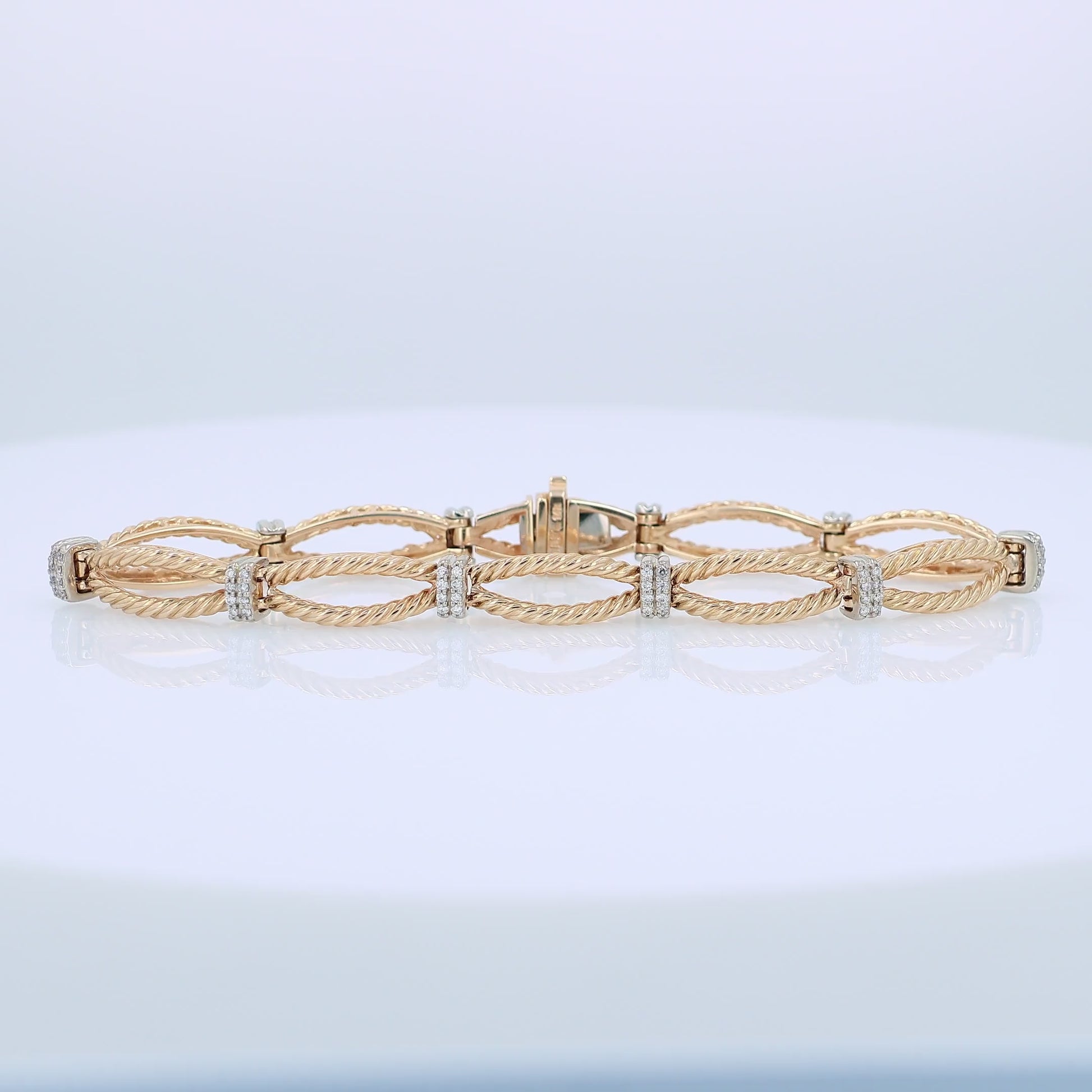 Gold bracelet with interlocking rope design links and alternating white gold diamond station accents on a white background
