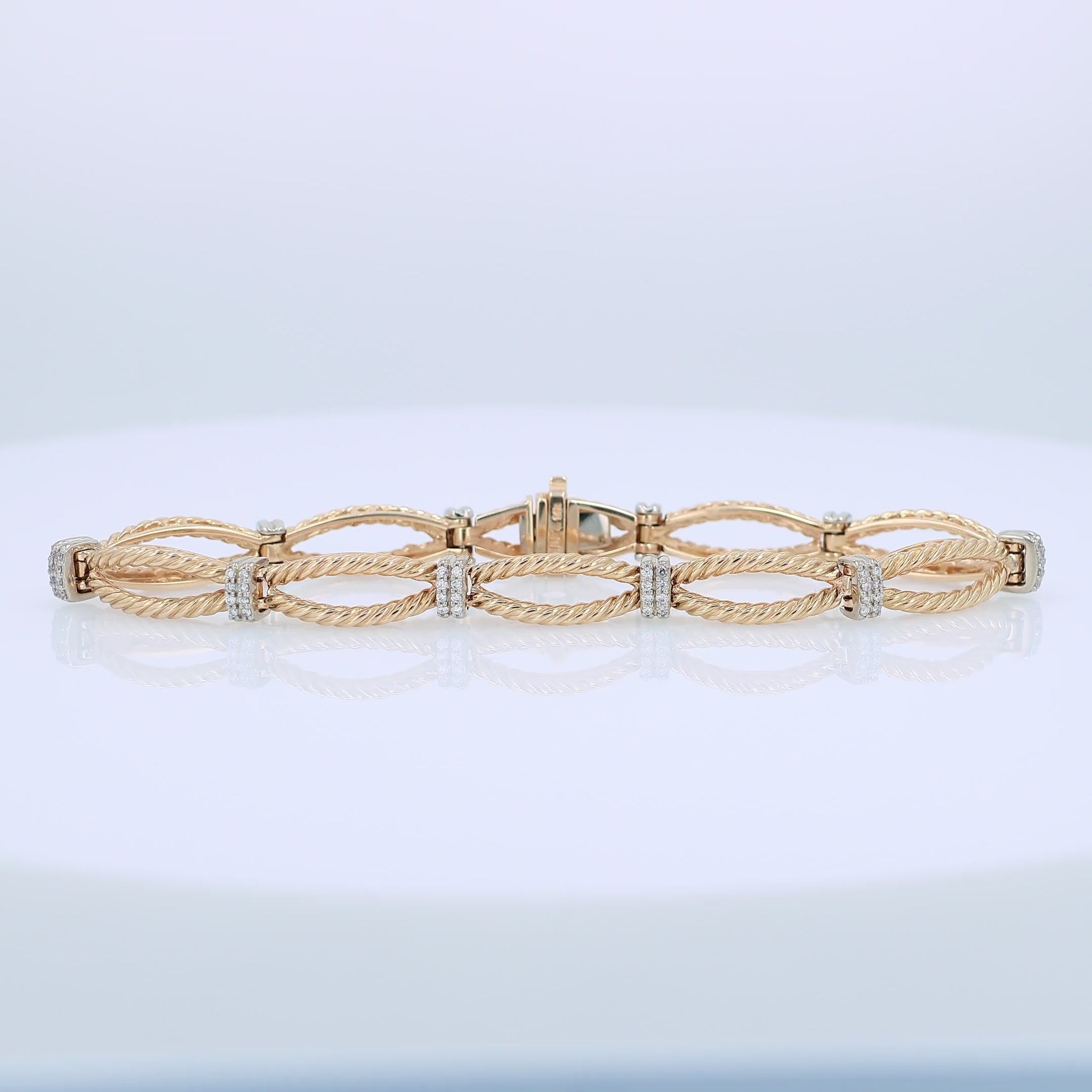Gold bracelet with interlocking rope design links and alternating white gold diamond station accents on a white background