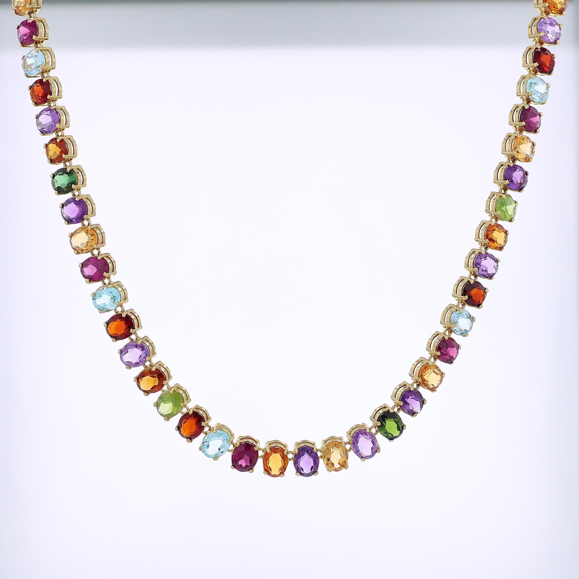 Yellow gold multicolored gemstone necklace on a white background