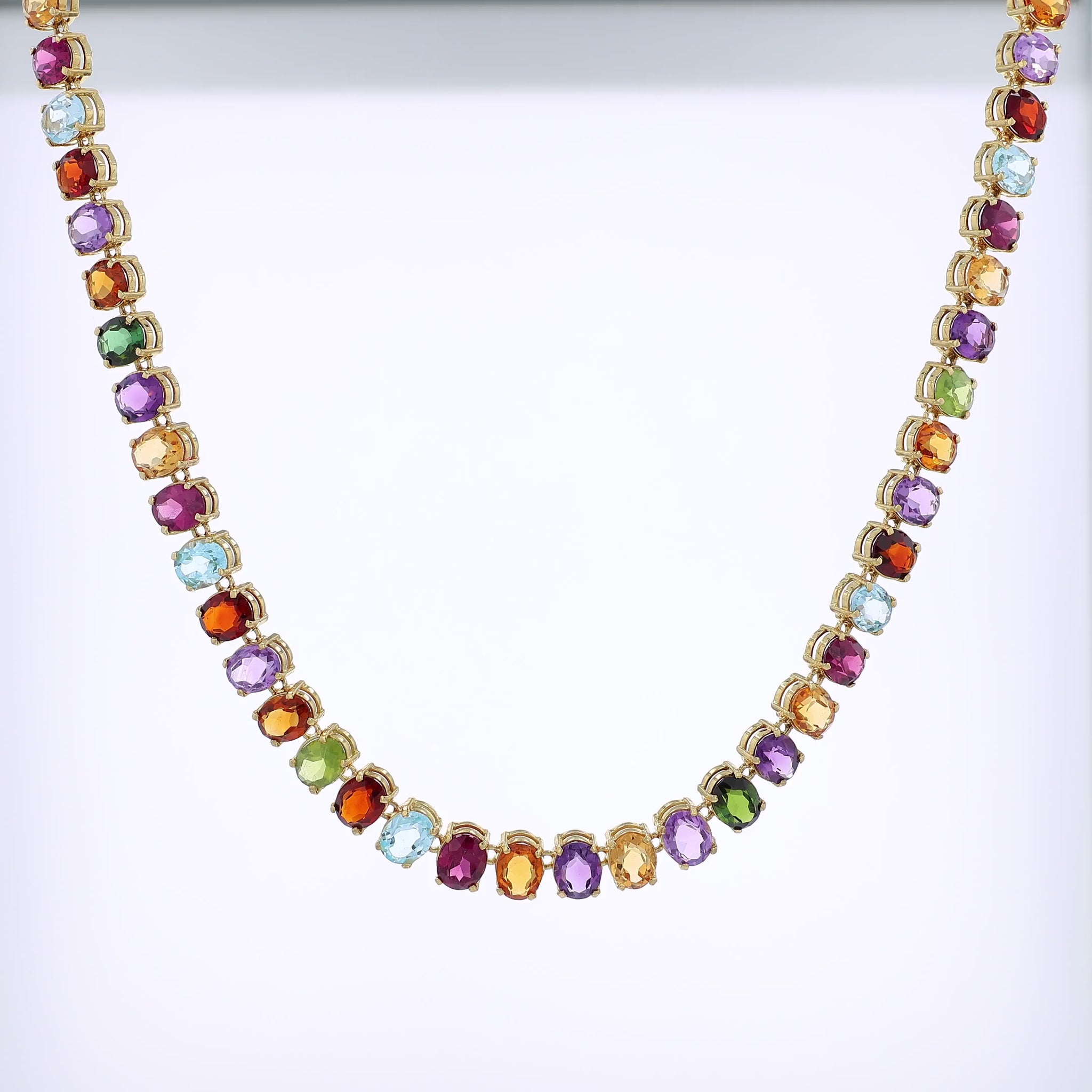 Yellow gold multicolored gemstone necklace on a white background