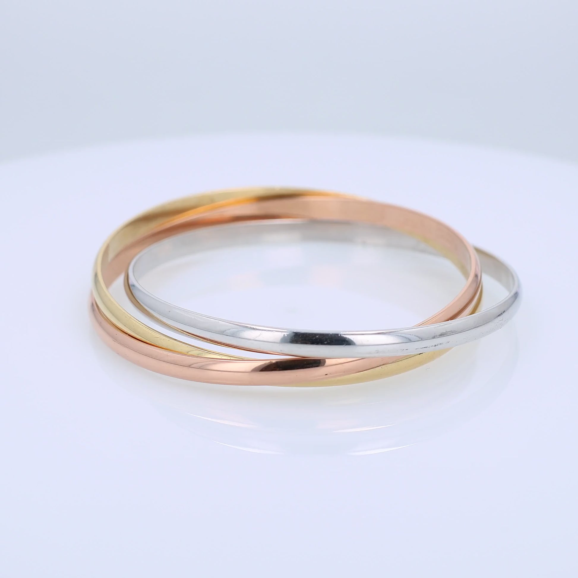 Tri-tone gold Cartier branded triple ring slip on bangle bracelet on a white background