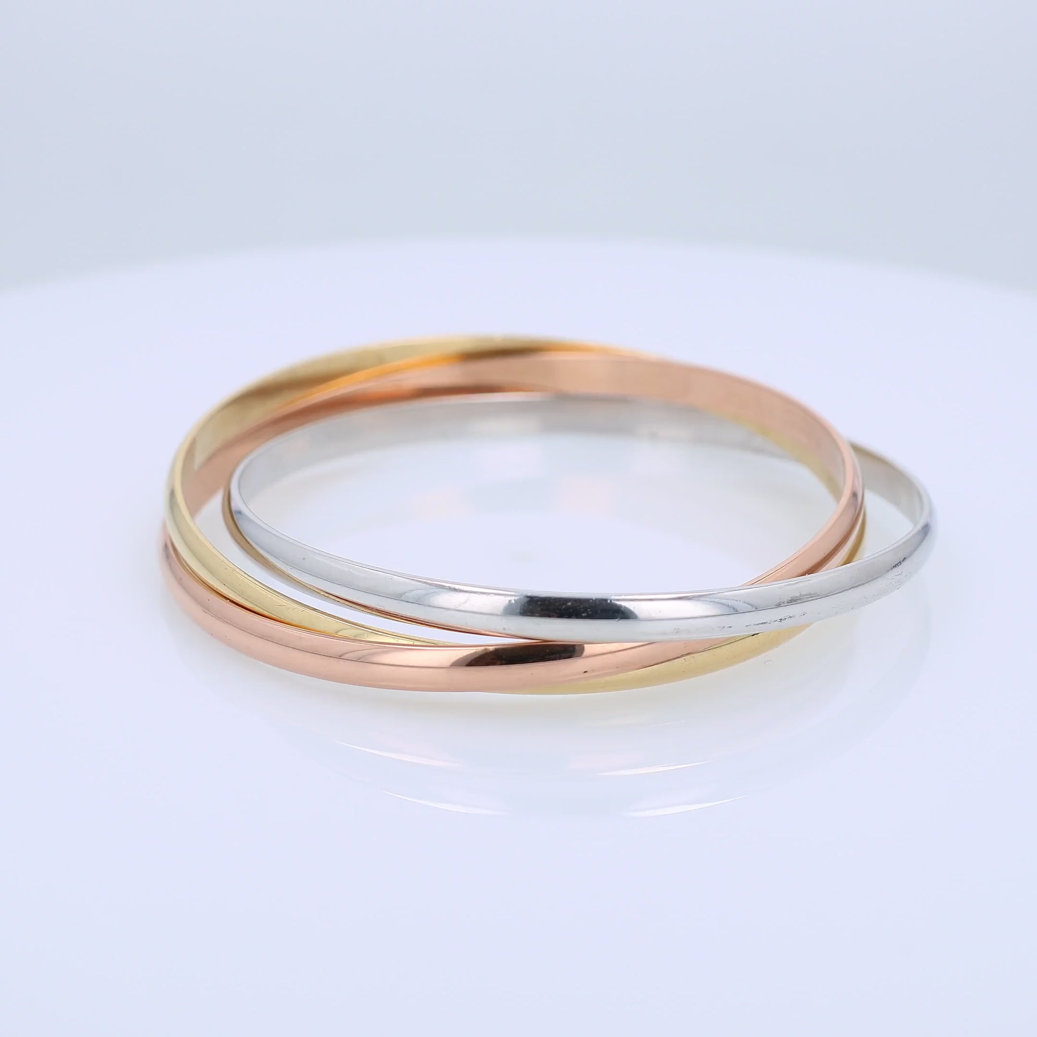 Tri-tone gold Cartier branded triple ring slip on bangle bracelet on a white background
