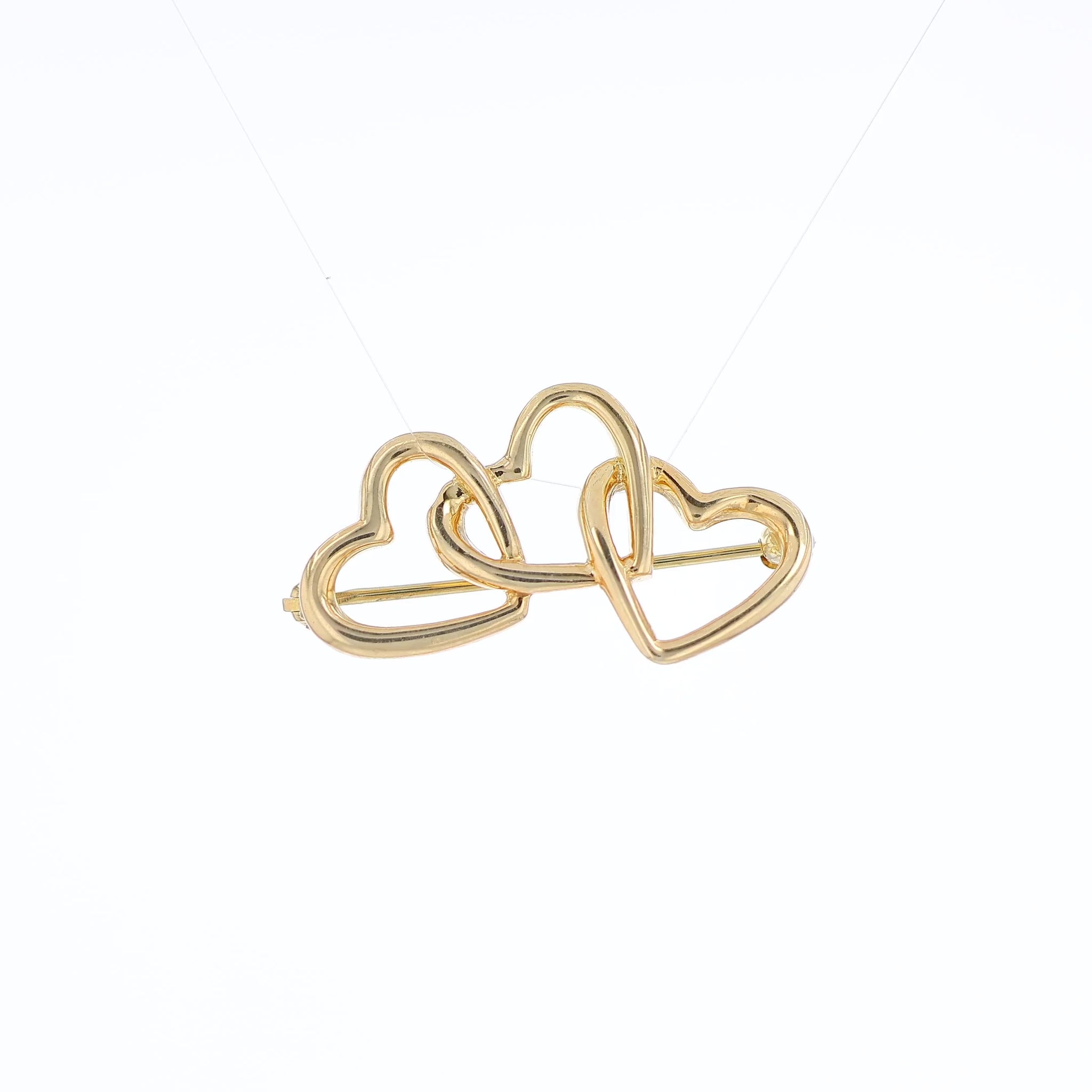 Yellow gold Tiffany & Co polished triple heart pin on a white background
