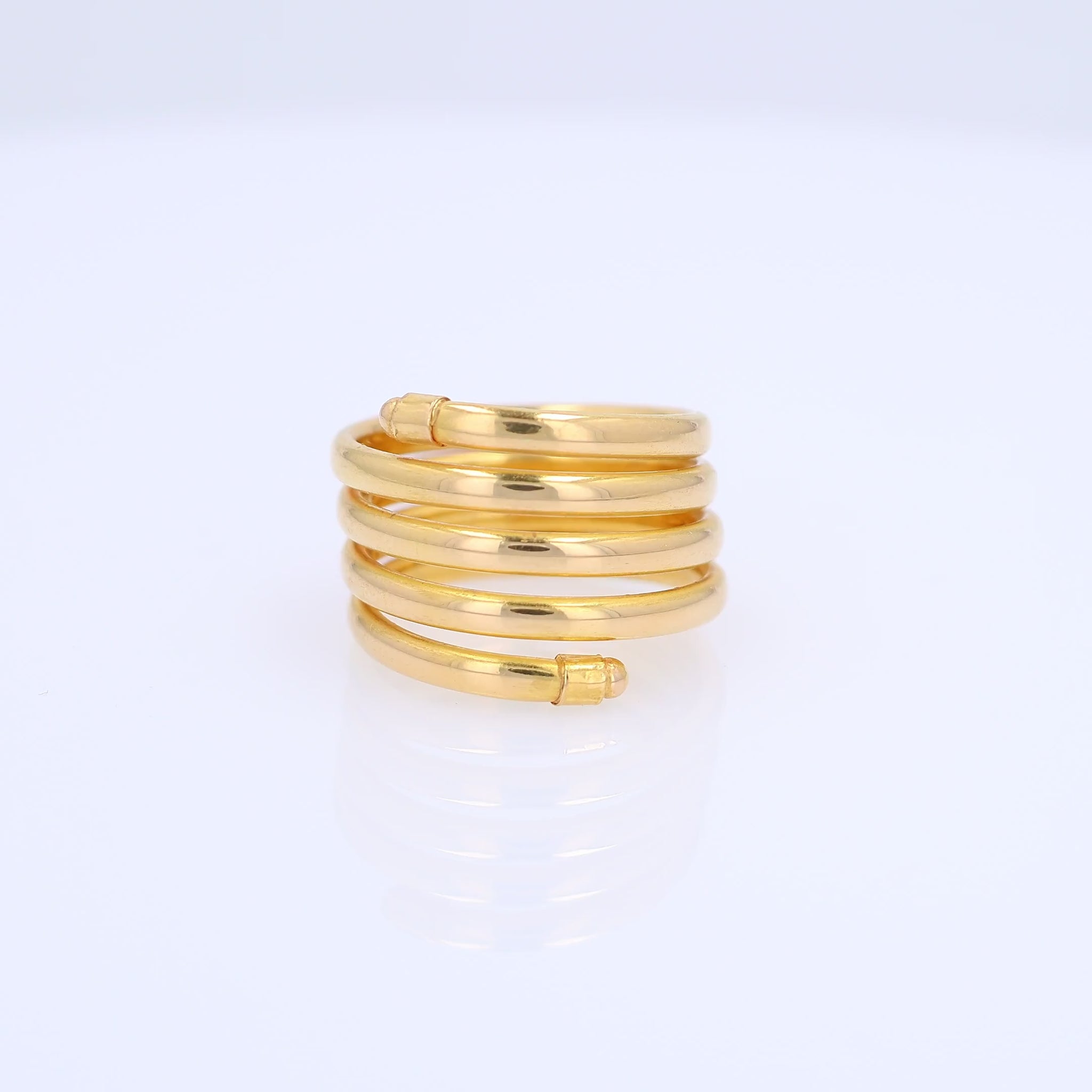 A gold wrap ring with multiple polished bands coiled around each other, shown on a clean white background.