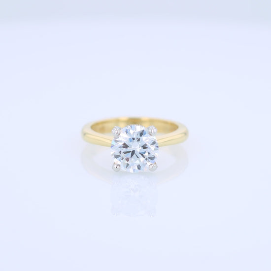 Yellow gold and platinum diamond engagement ring with diamond accents and a round cubic zirconia center on a white background