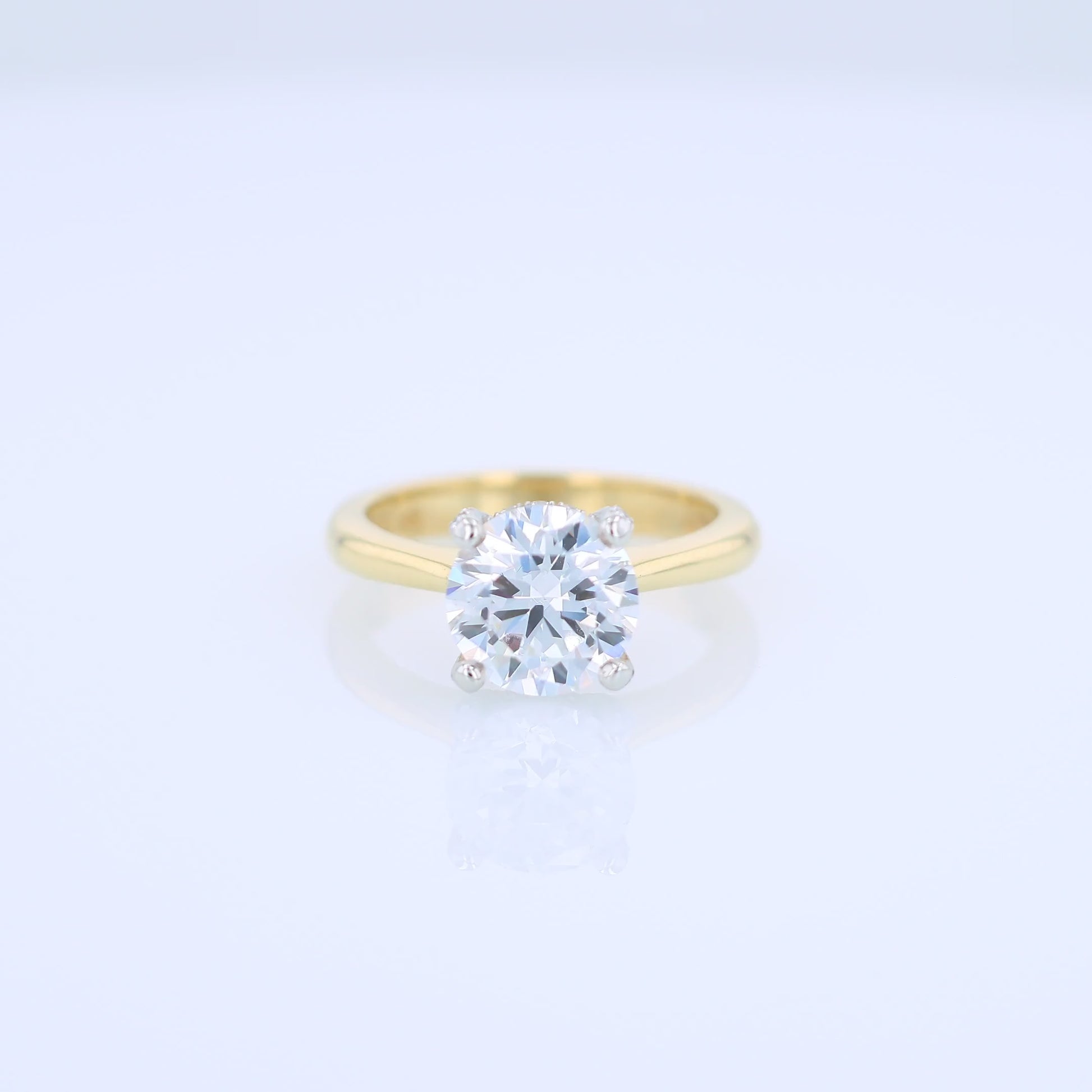 Yellow gold and platinum diamond engagement ring with diamond accents and a round cubic zirconia center on a white background