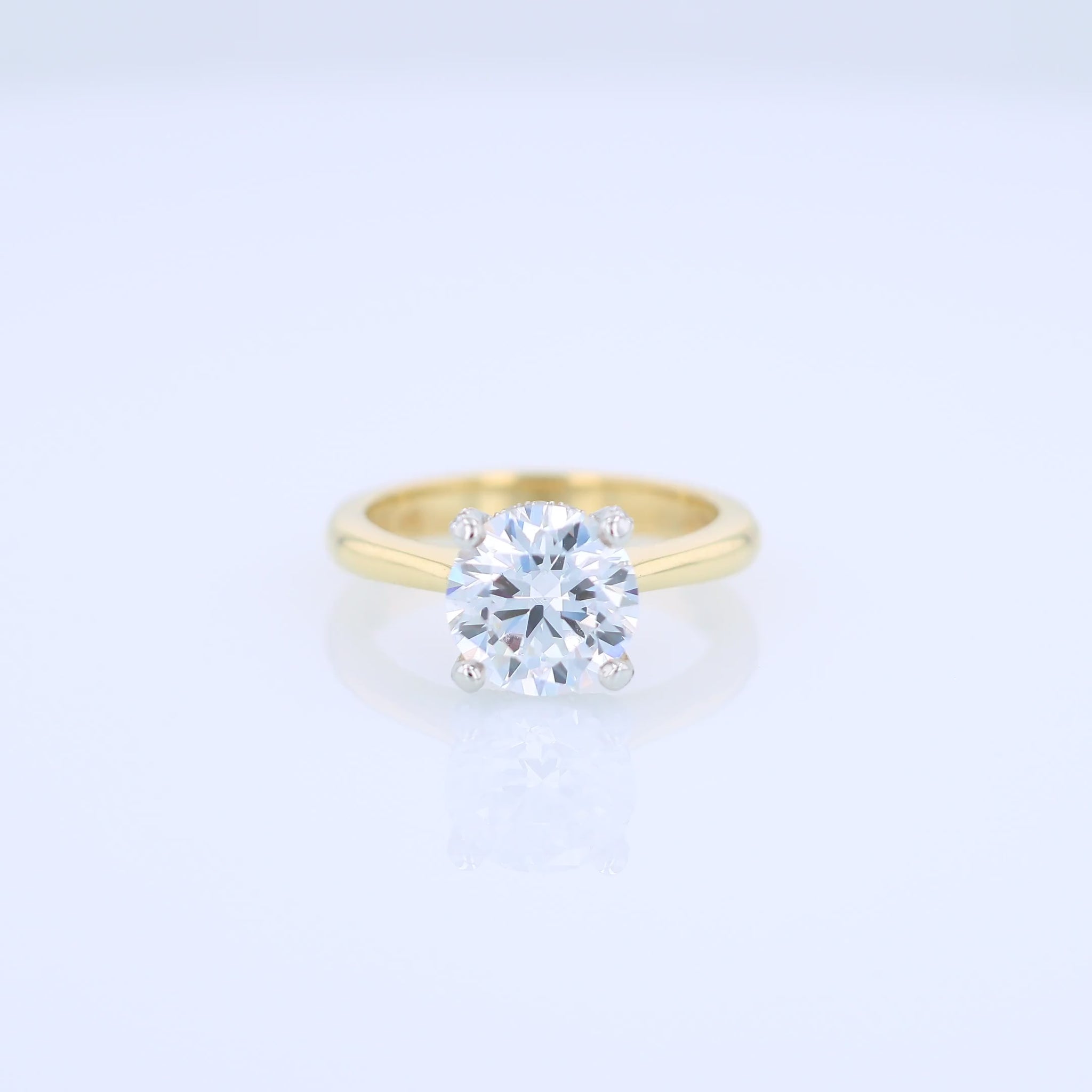 Yellow gold and platinum diamond engagement ring with diamond accents and a round cubic zirconia center on a white background