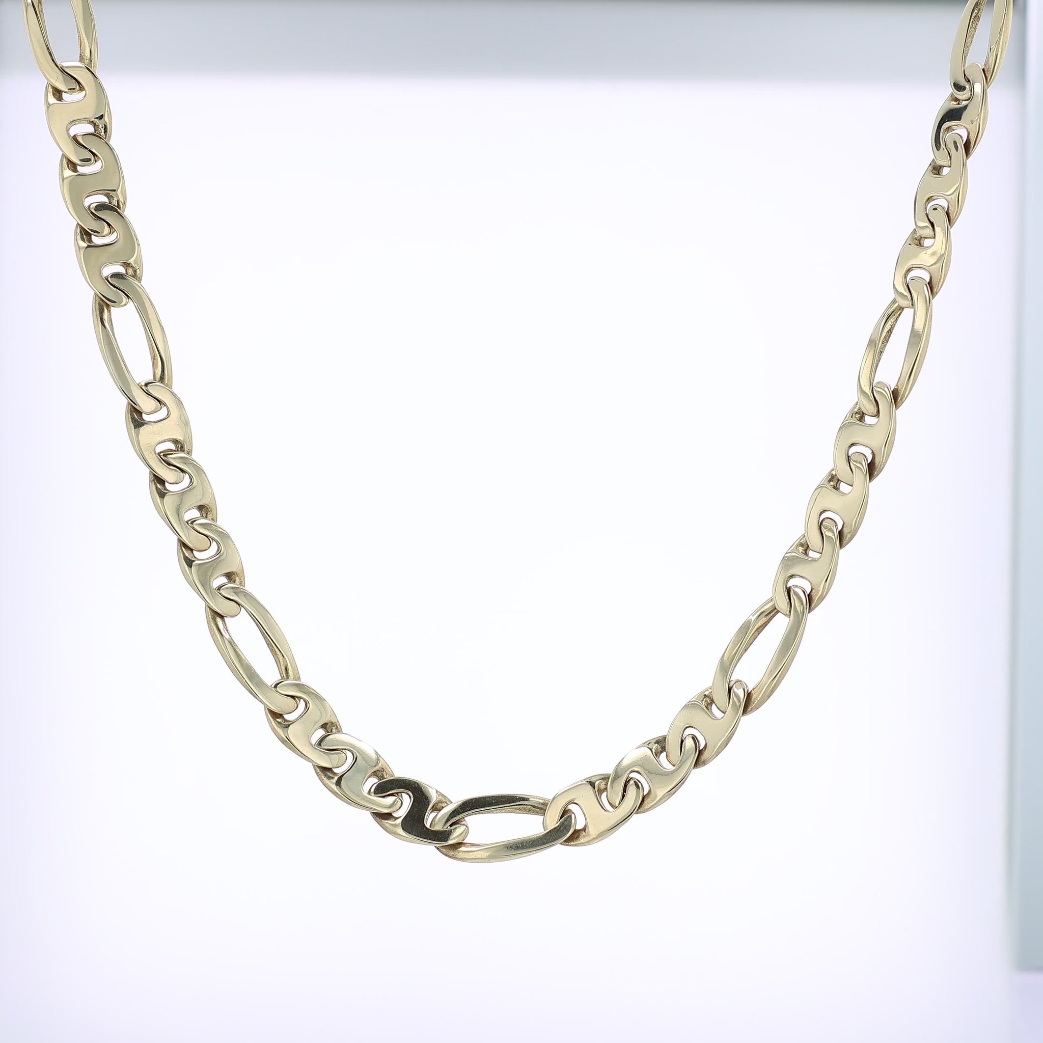 Yellow gold figaro link chain necklace on a white background