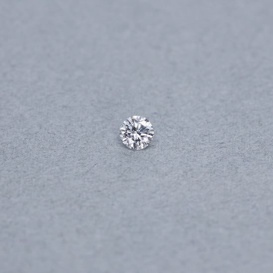 Round .68 carat diamond graded FVS2 on a grey background