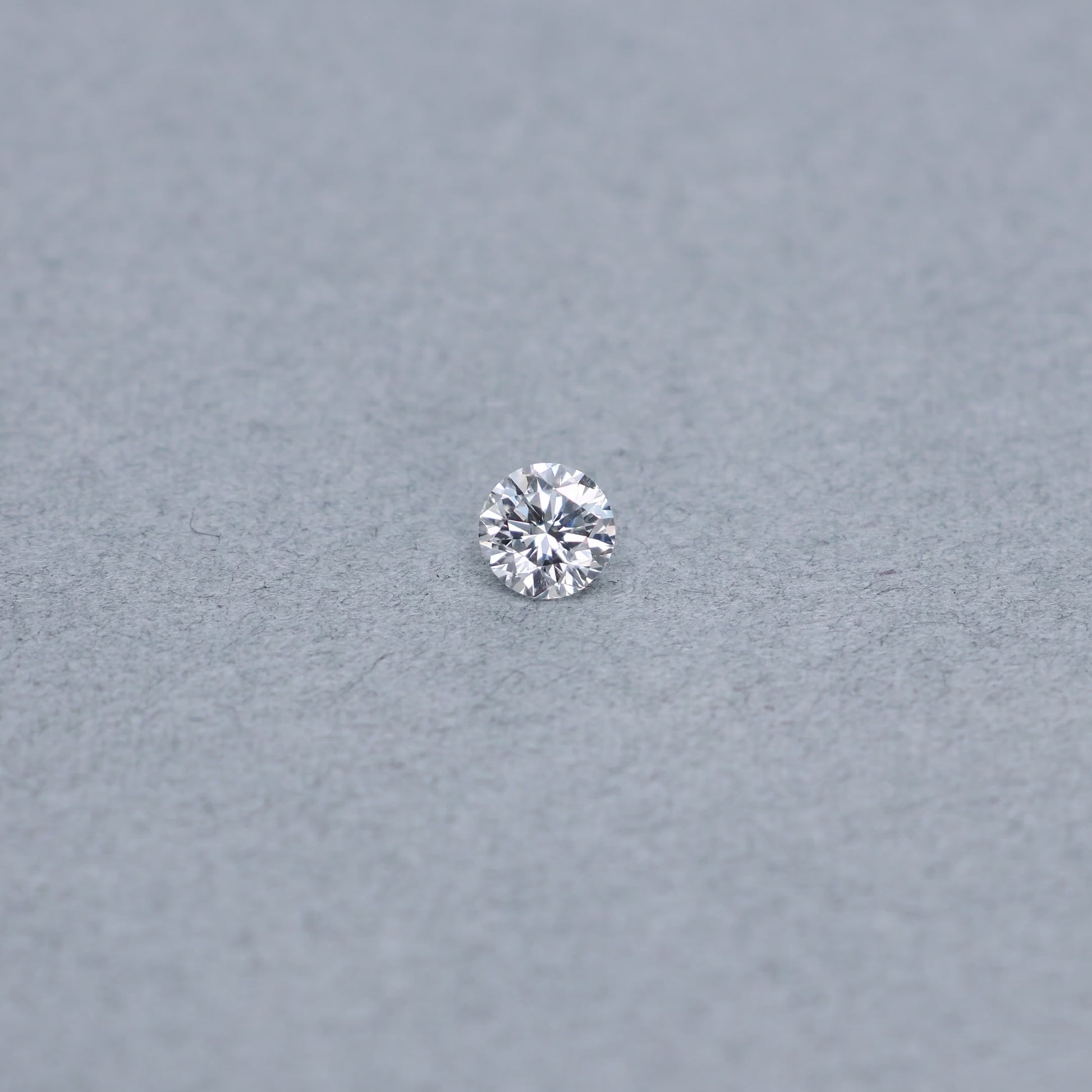 Round .68 carat diamond graded FVS2 on a grey background