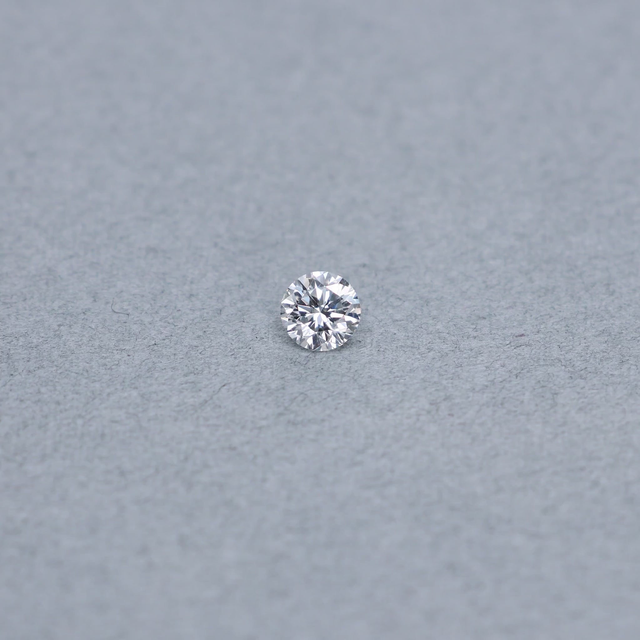 Round .68 carat diamond graded FVS2 on a grey background