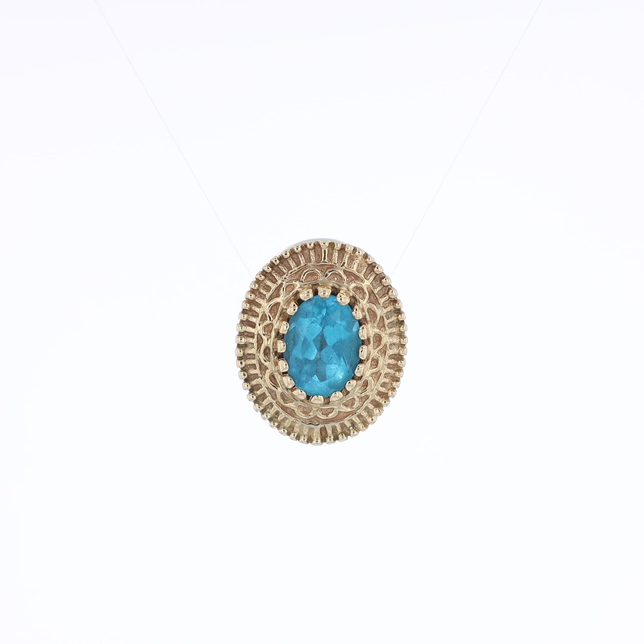 Yellow gold oval blue topaz slide charm pendant with a textured front on a white background