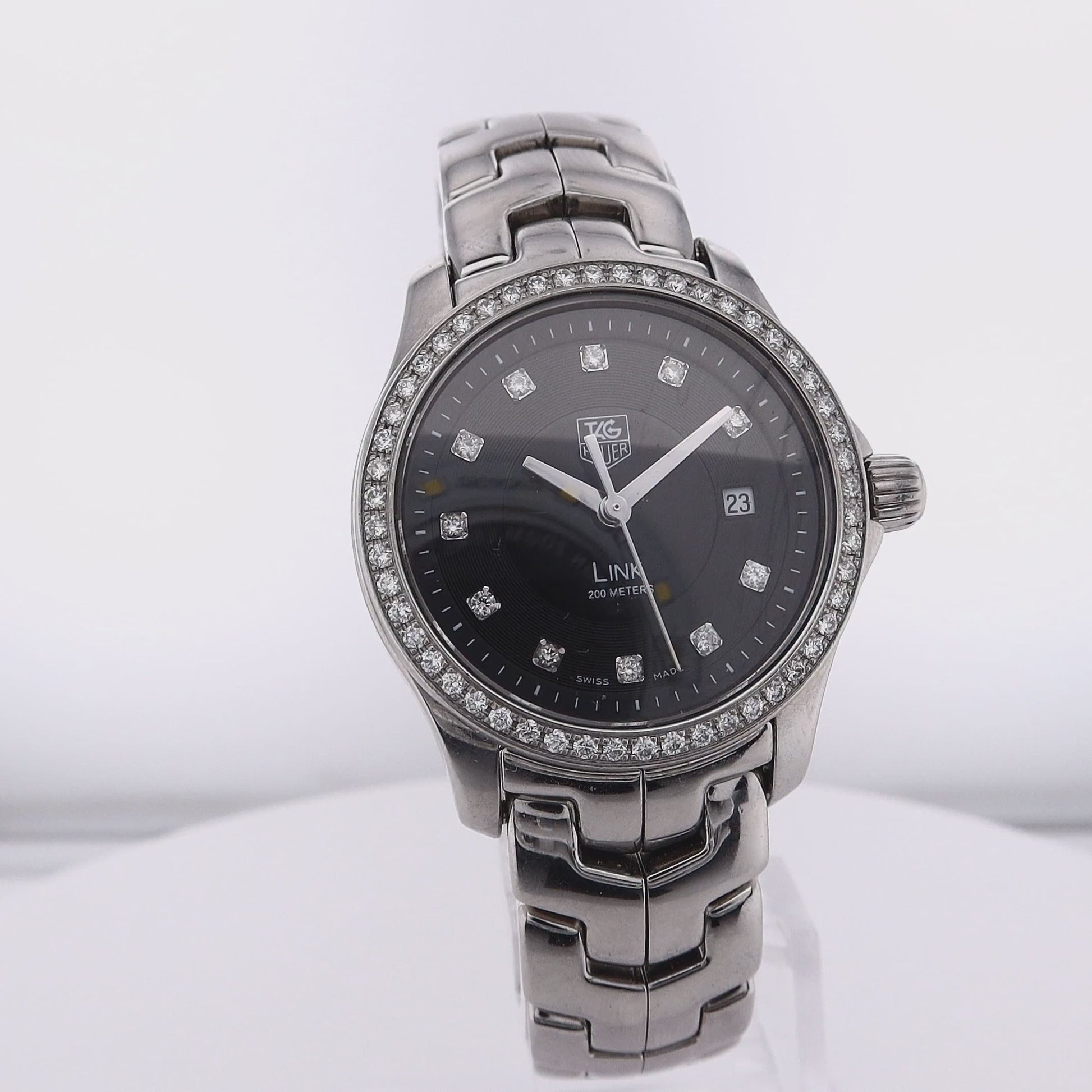 360 degree video of a silver TAG Heuer watch with a black dial, diamond indexes, and diamond bezel on a white background