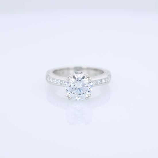 Platinum diamond engagement ring with diamond accents and a round cubic zirconia center on a white background