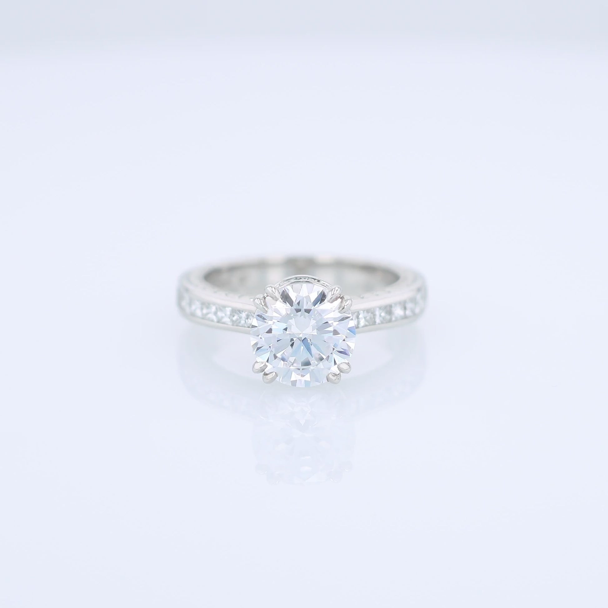 Platinum diamond engagement ring with diamond accents and a round cubic zirconia center on a white background