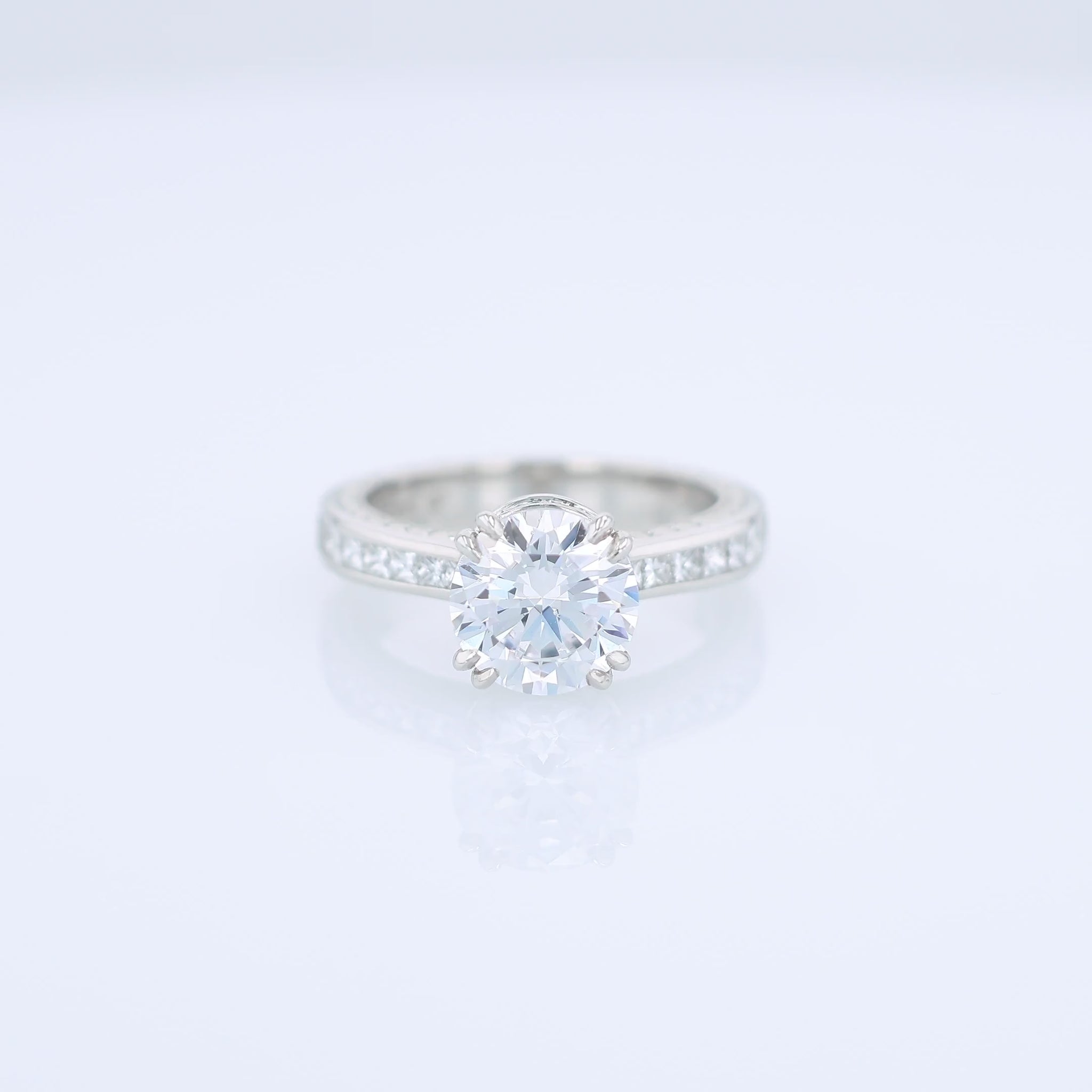 Platinum diamond engagement ring with diamond accents and a round cubic zirconia center on a white background