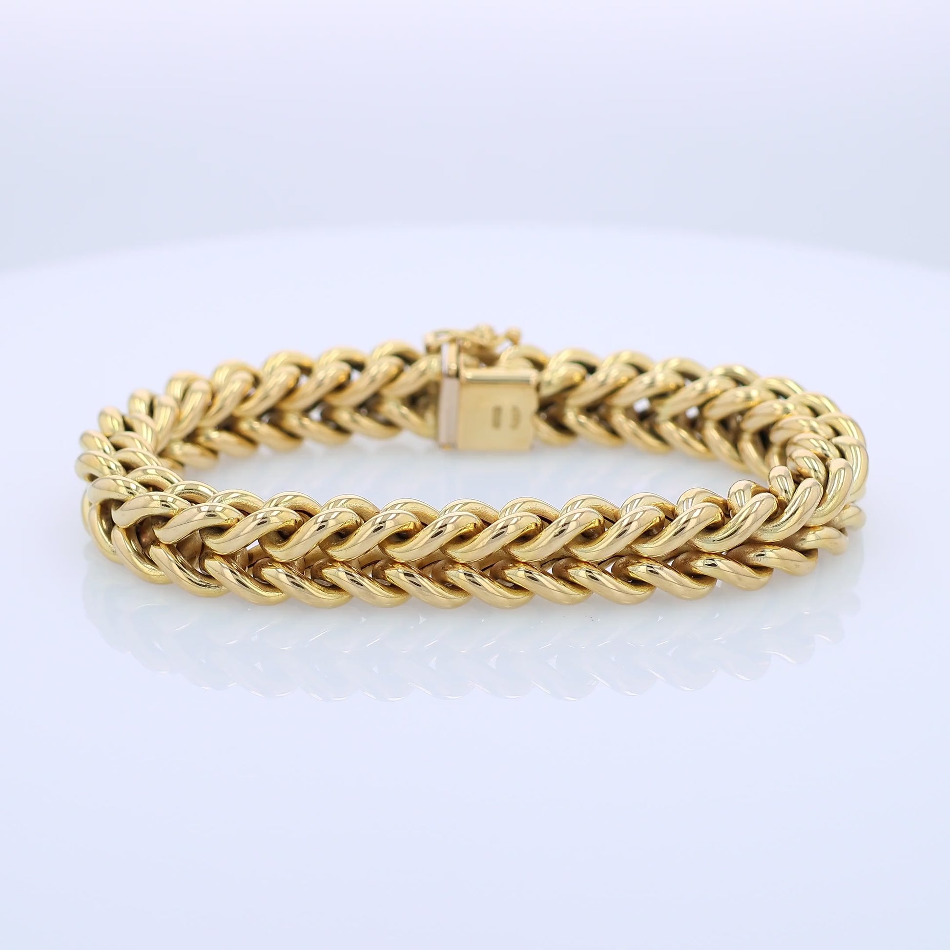 Yellow gold braided link chain bracelet on a white background