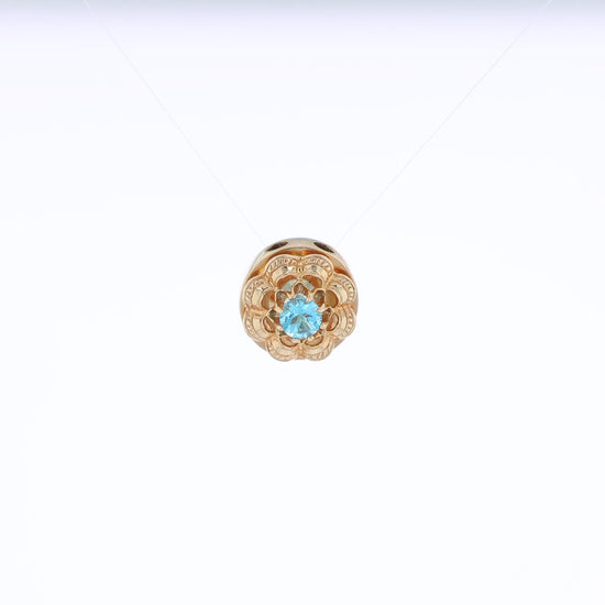 Yellow gold Victorian slide pendant with a blue topaz center and scalloped border on a white background