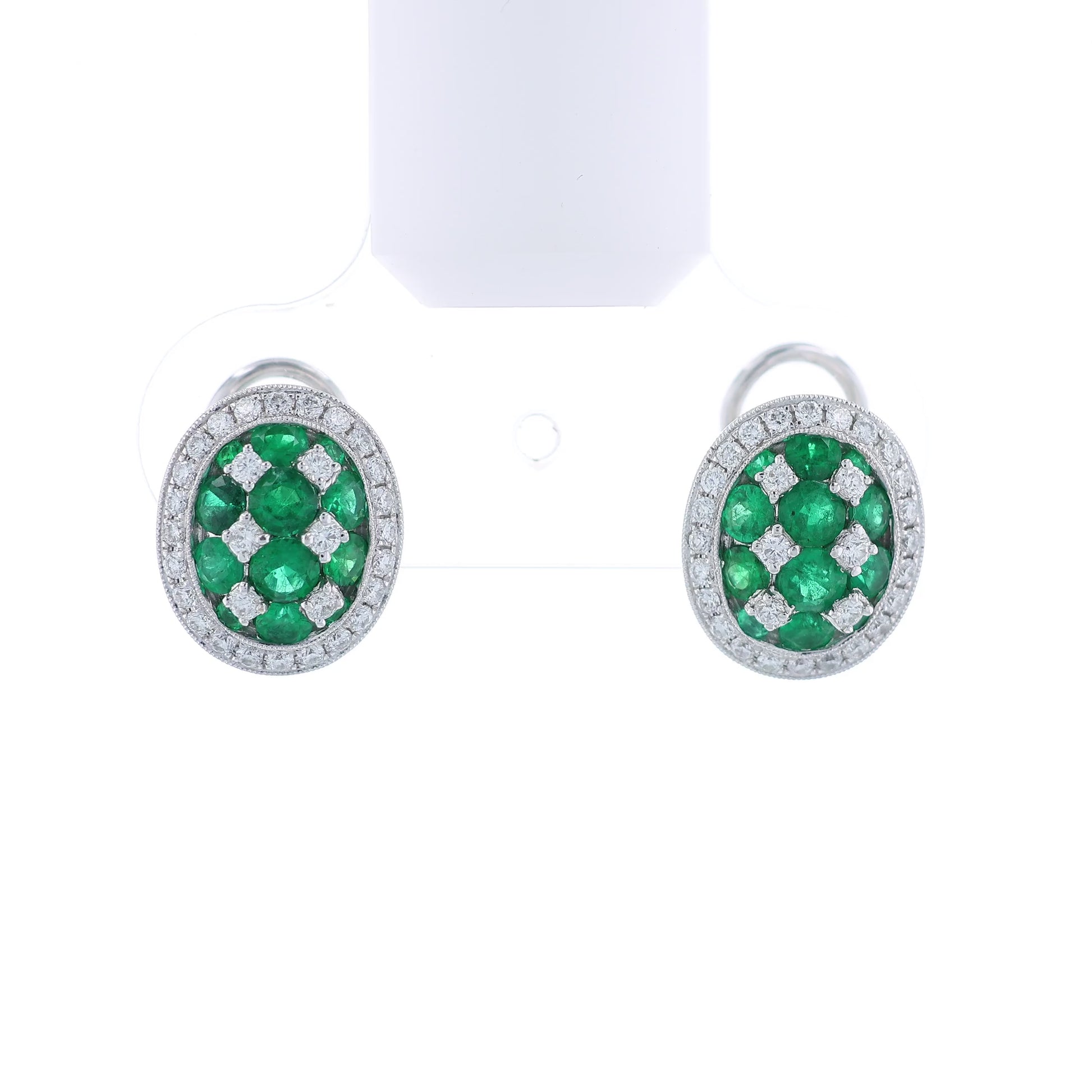 Pair of white gold emerald and diamond halo stud earrings on a white background