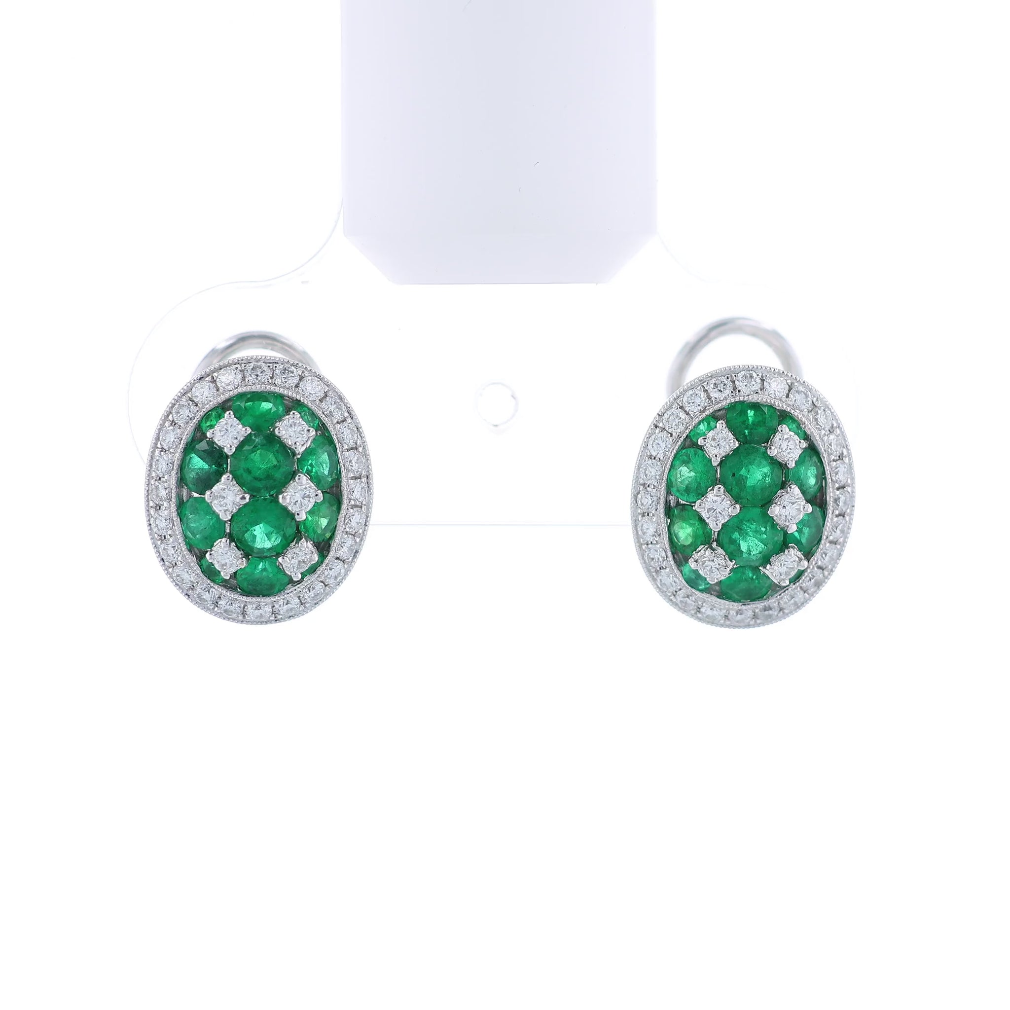 Pair of white gold emerald and diamond halo stud earrings on a white background
