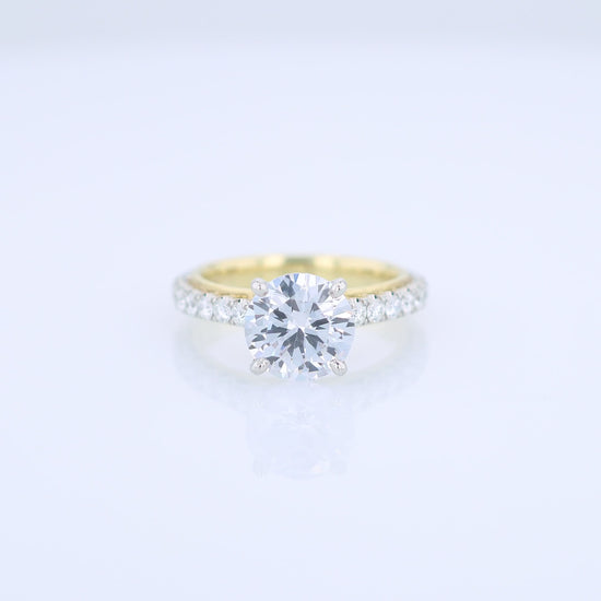 Two-tone diamond engagement ring with diamond accents and a round cubic zirconia center on a white background