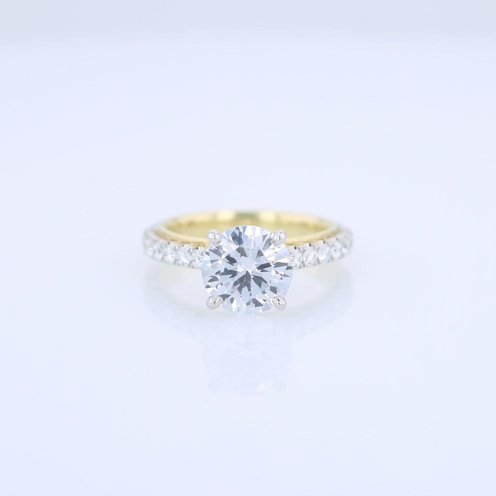 Two-tone diamond engagement ring with diamond accents and a round cubic zirconia center on a white background