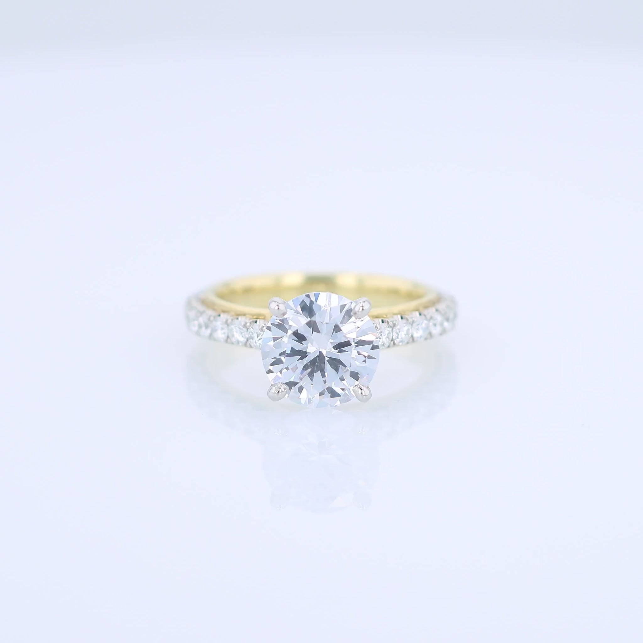 Two-tone diamond engagement ring with diamond accents and a round cubic zirconia center on a white background