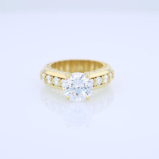 Yellow gold diamond engagement ring with diamond accents and a round cubic zirconia center on a white background