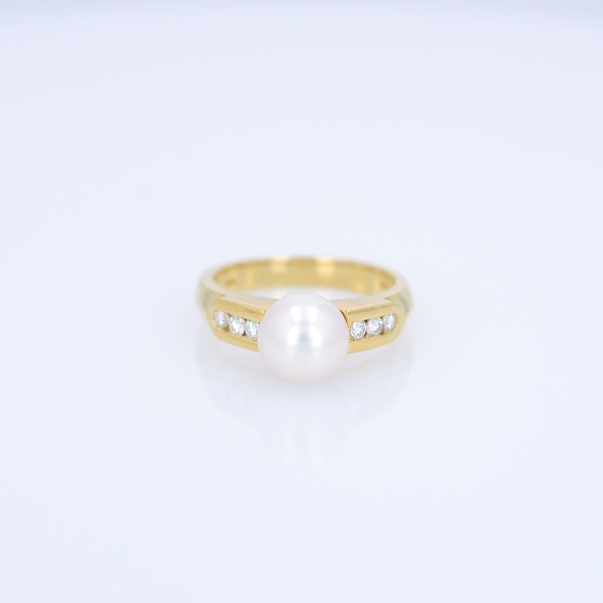 Yellow gold akoya pearl and diamond row ring on a white background
